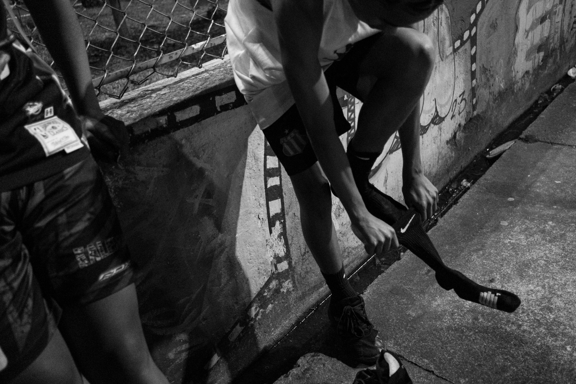 Kaleman Boys -  Pietro Santos de Souza puts on a sock given by Rodrigo Santana at the Kaleman basketball court,...