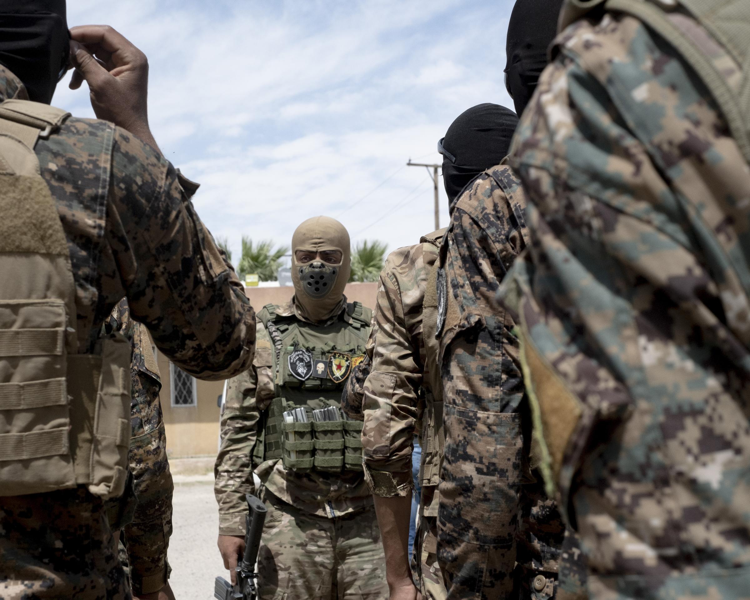 On National Geographic: 11 years into Syria's civil war, this is what life looks like - YPG commander Hezat (center) speaks with his troops in Deir Ez-Zor in May 2021. The Kurdish...