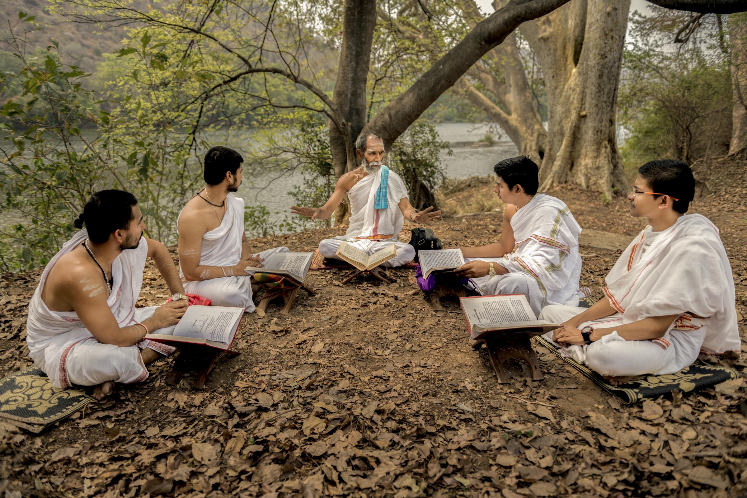 Vedic Guru teaches Yajurveda to senior students of Gurukula. The early Vedic teachers attached great importance to studying under trees. Om-Shantidhama Gurukula, Kanakapura, Karnataka, India.