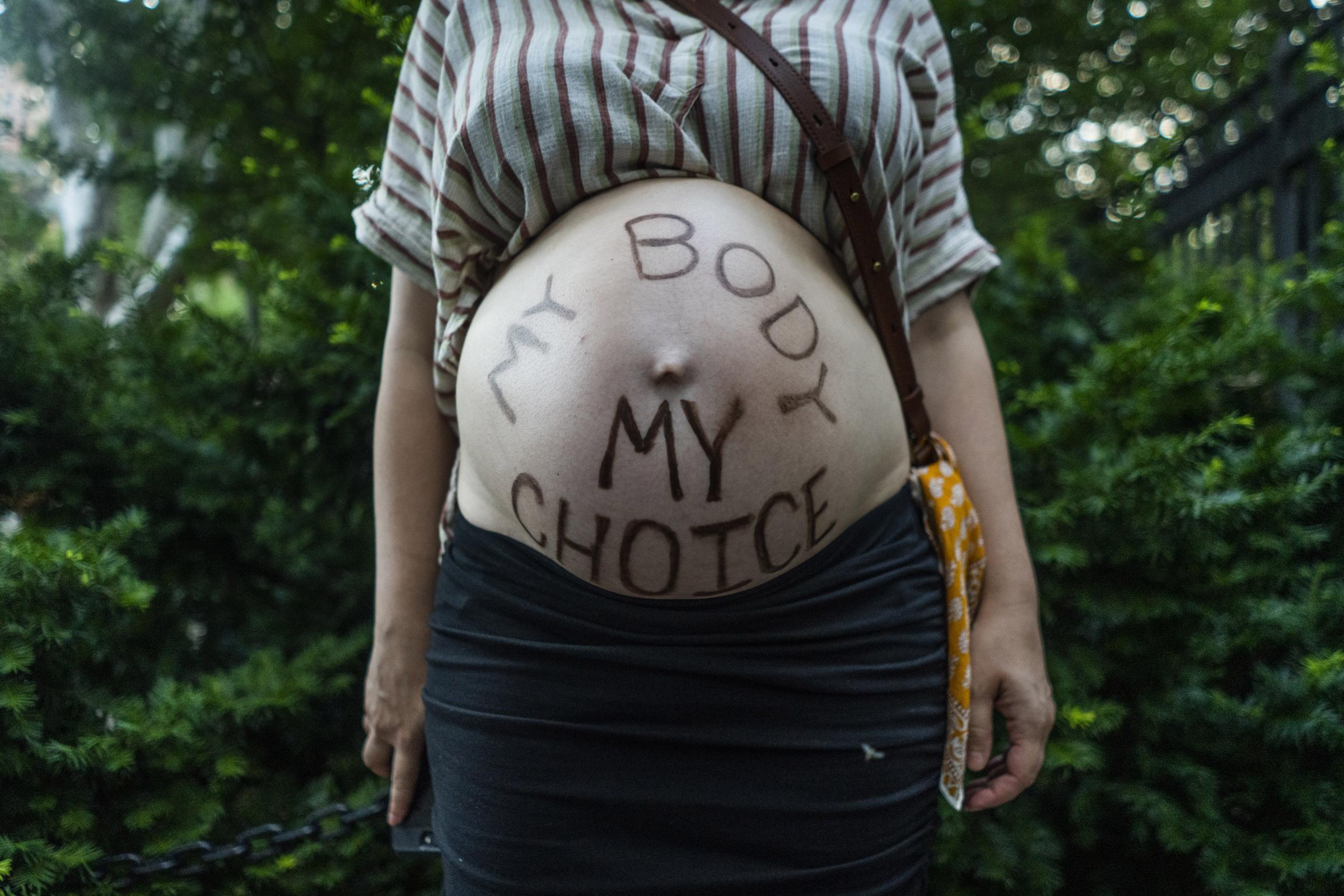 A woman has &quot;My Body, My Choice&quot; written on her pregnant belly during a protest against the Supreme Court&rsquo;s decision to...