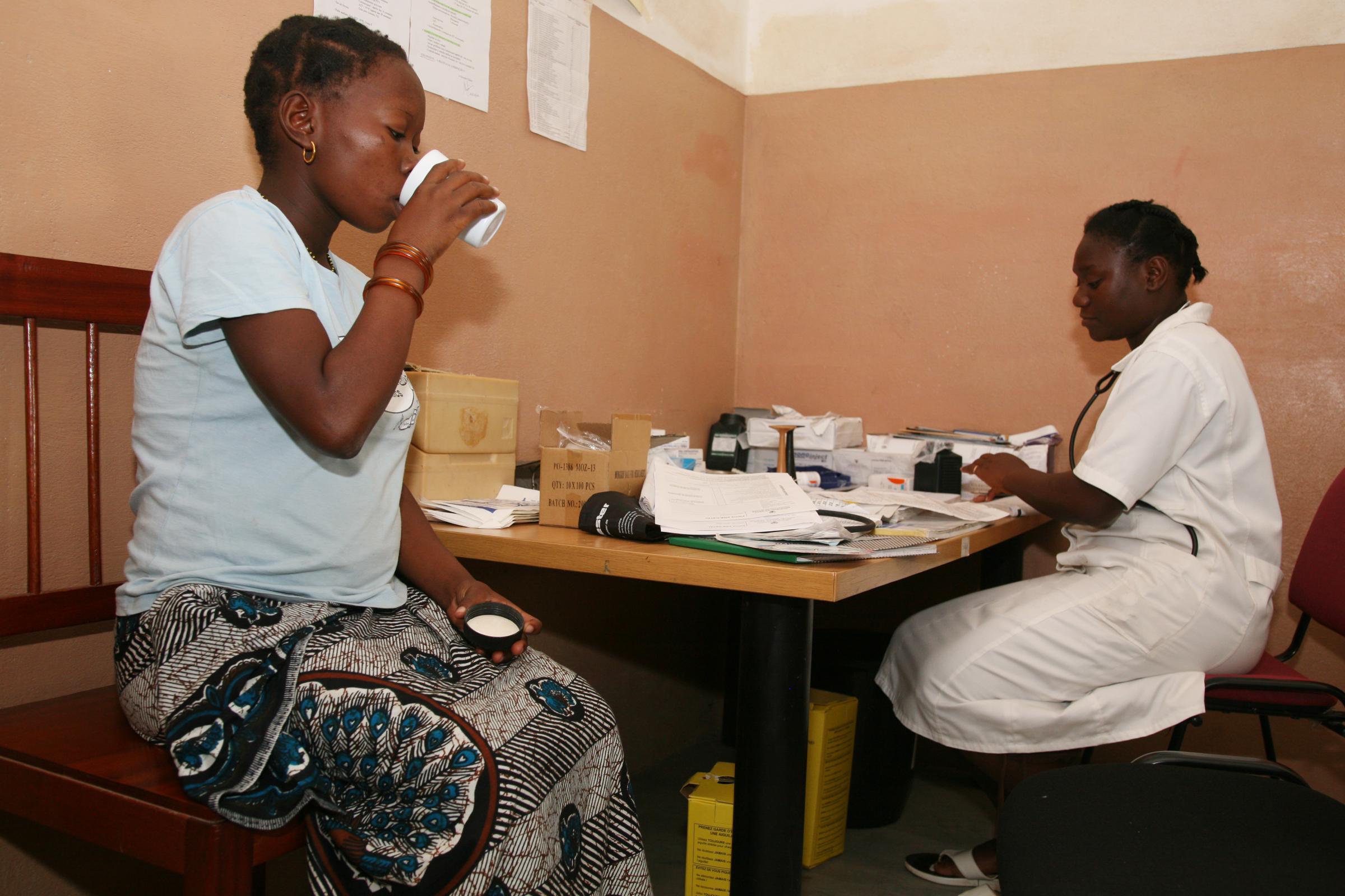 Malaria - A HIV patient takes her medication on her medical...