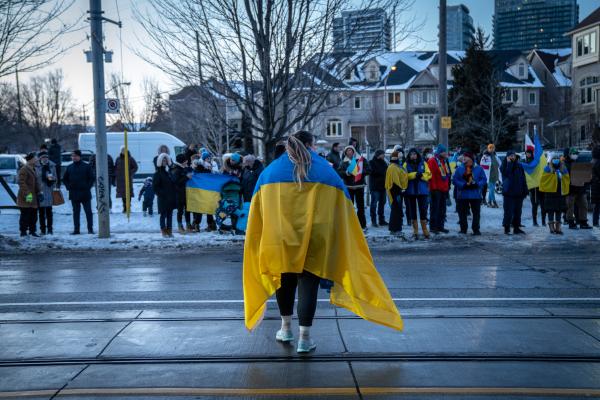 Image from [Ongoing] Ukrainian Toronto Protests - A woman protestor wearing a Ukrainian flag around her...