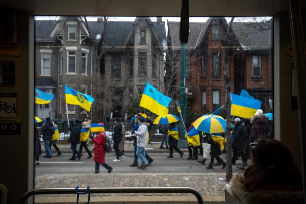 Image from [Ongoing] Ukrainian Toronto Protests - People holding Ukrainian flags pass by the window of a...