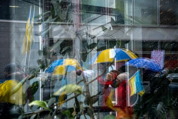 Image from [Ongoing] Ukrainian Toronto Protests - A reflection of people holding blue and yellow umbrellas...