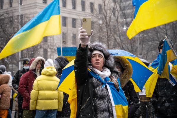 Image from [Ongoing] Ukrainian Toronto Protests - A woman wearing a Ukrainian flag holding up her phone to...