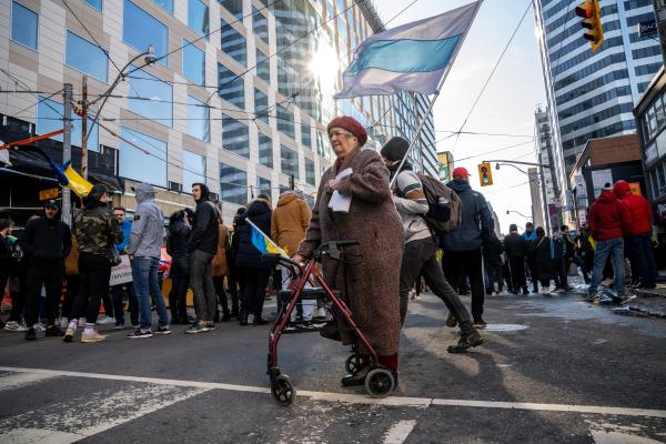 Image from [Ongoing] Ukrainian Toronto Protests - An elderly woman with a stroller stands in silence during...