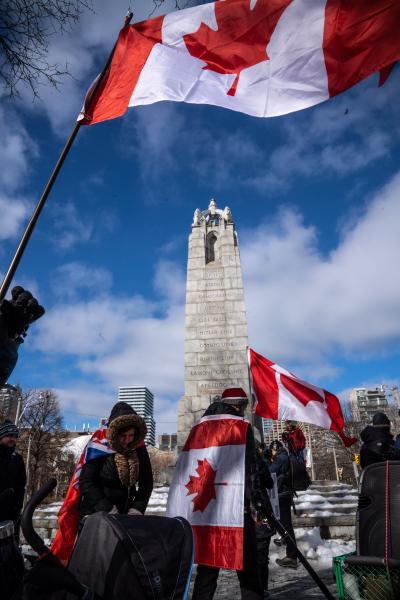 Protestors waving Canadian flags in front of a pillar. Trucker convoy protesters gather in Queen’s Park, Toronto for the second consecutive weekend in solidarity with anti-mandate demonstrations on February 12, 2021. It comes after the province declared a state of emergency in relation to the ongoing blockades, with Toronto police setting up road closures across the city.