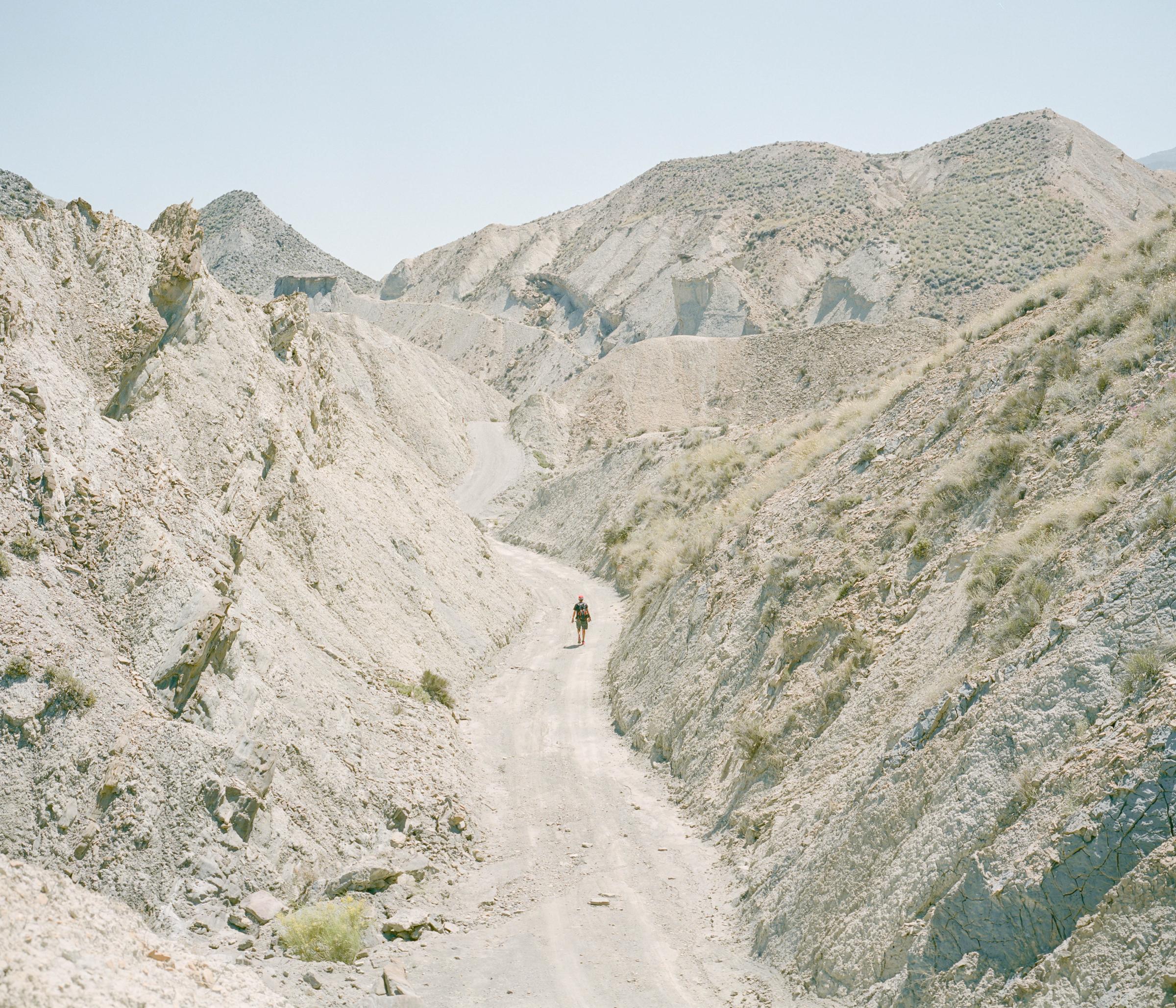 Eroding Franco (Árida) - A hiker traverses a barren hill in the arid expanse of...