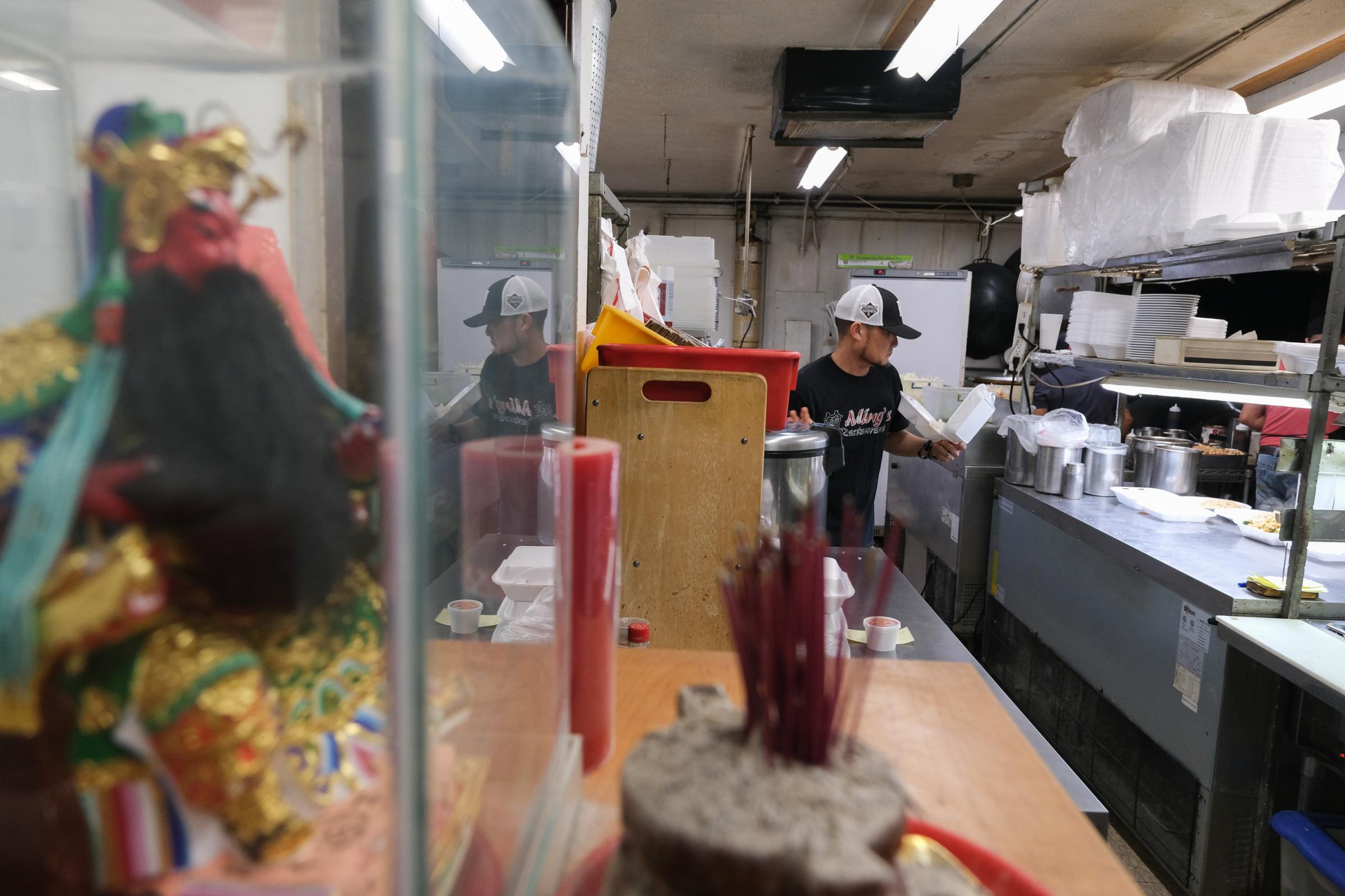 PAPILLION, NE - MARCH 18, 2022: Ping Wang prepares orders in the kitchen of Ming&#39;s Restaurant in Papillion, Nebraska on March 18, 2022. A shrine dedicated to Ming Wang is seen on the left. (Photo by Arin Yoon for The Washington Post) Papillion United States