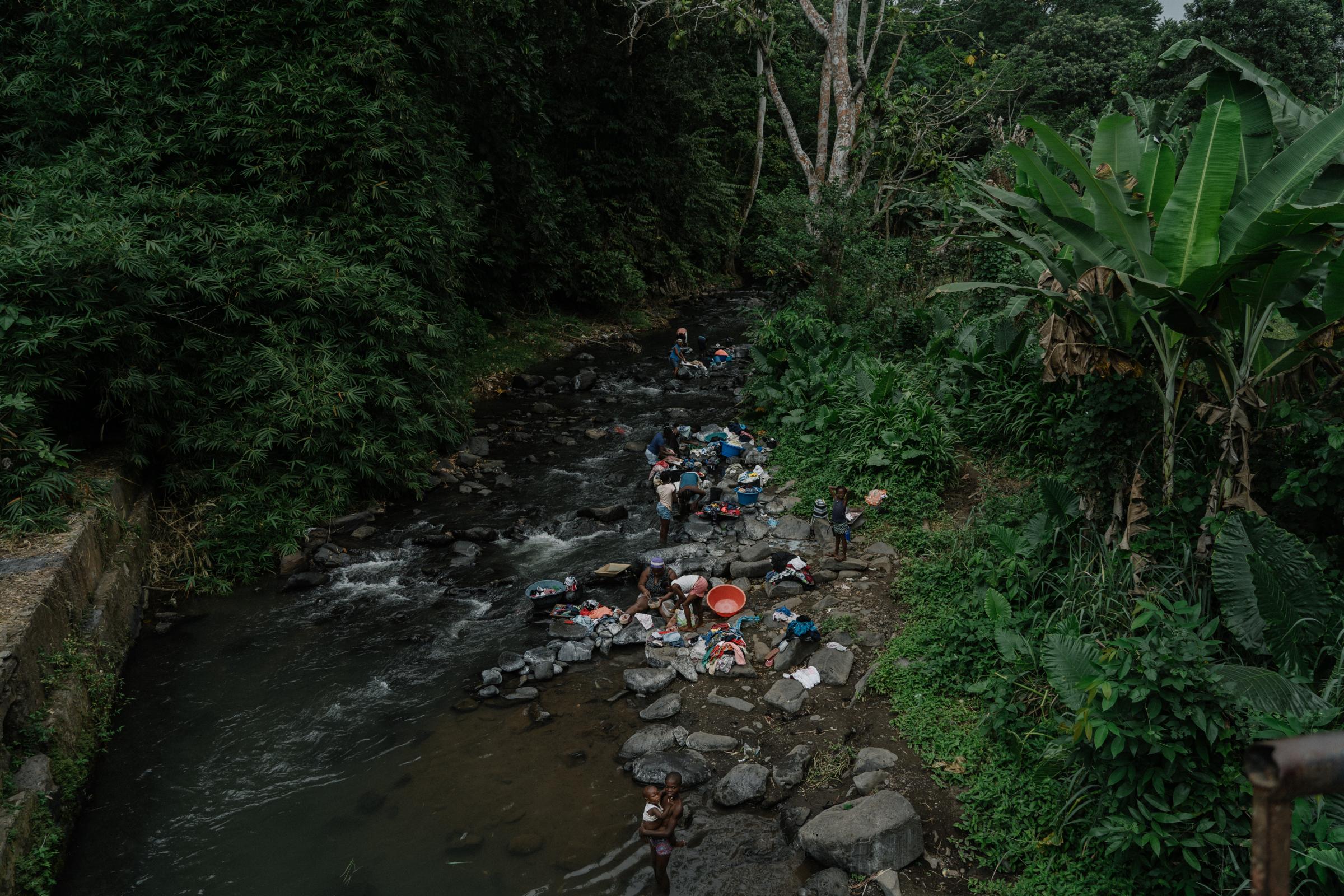 Genetic Engineering In the Mosquito War - Women wash their clothes in the river, São...