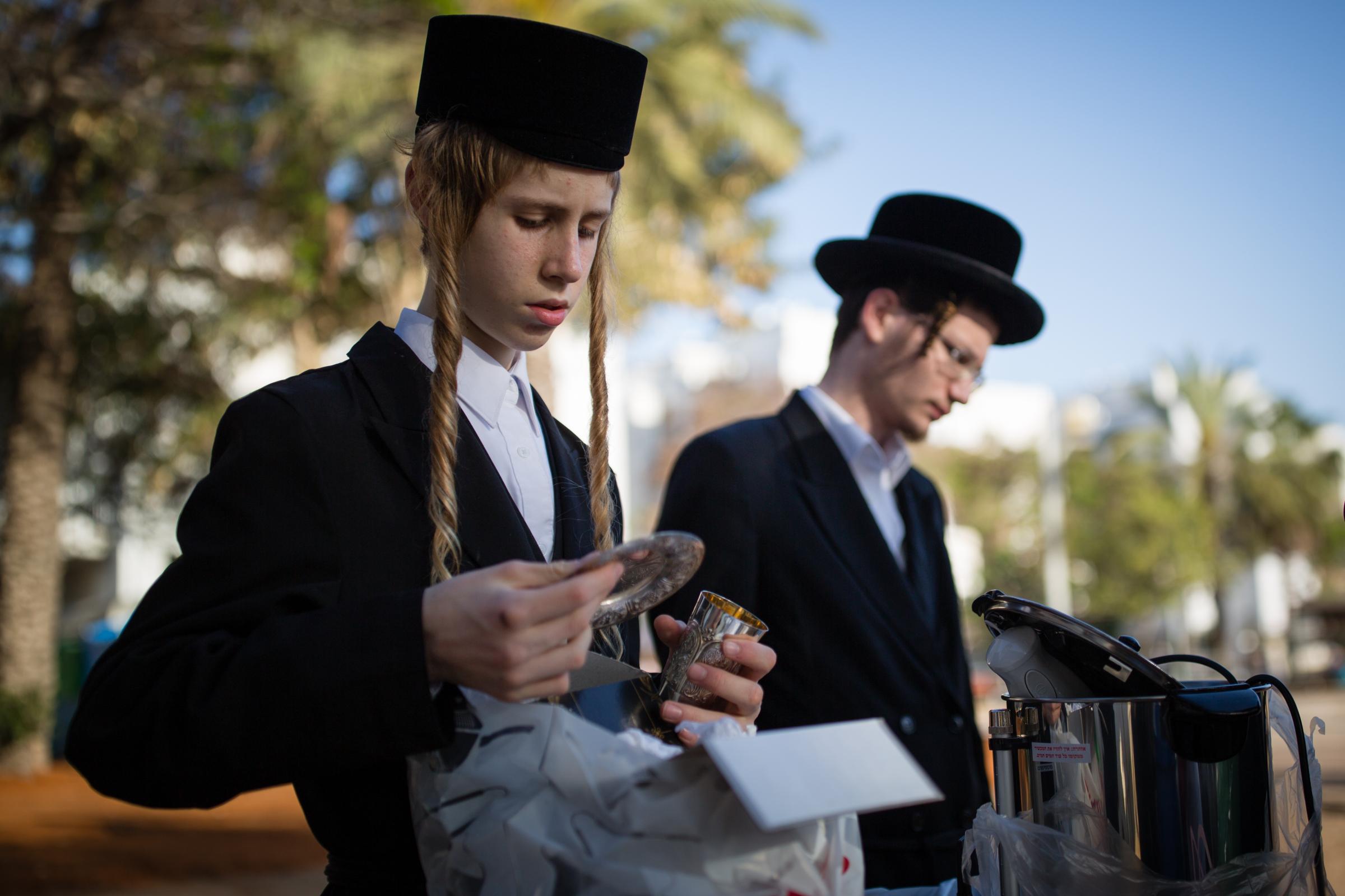 Ultra-Orthodox Community - An ultra-Orthodox Jewish inspects cutlery before dipping...