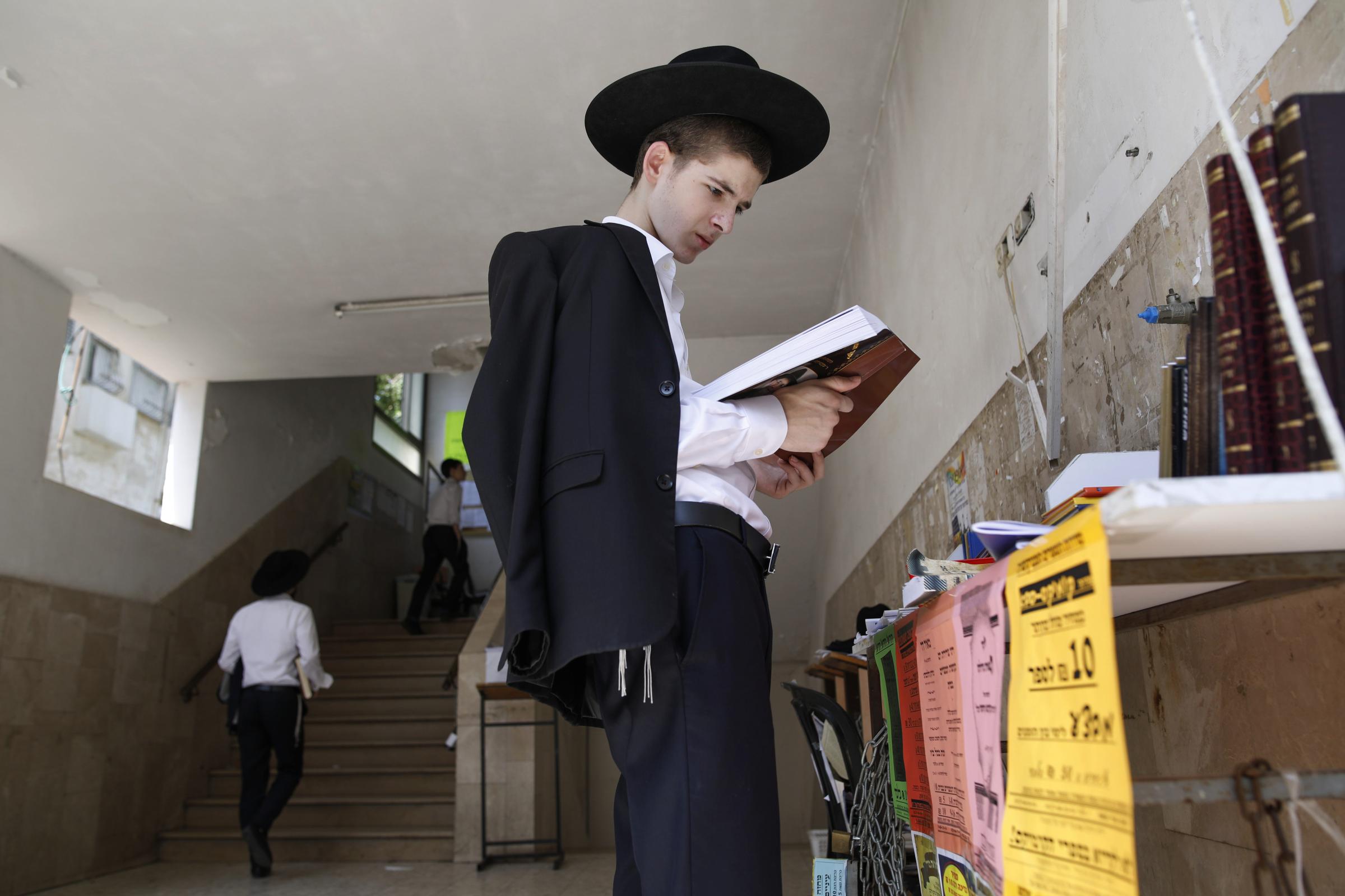 Ultra-Orthodox Community - An ultra-orthodox Jewish man reads a book while standing...