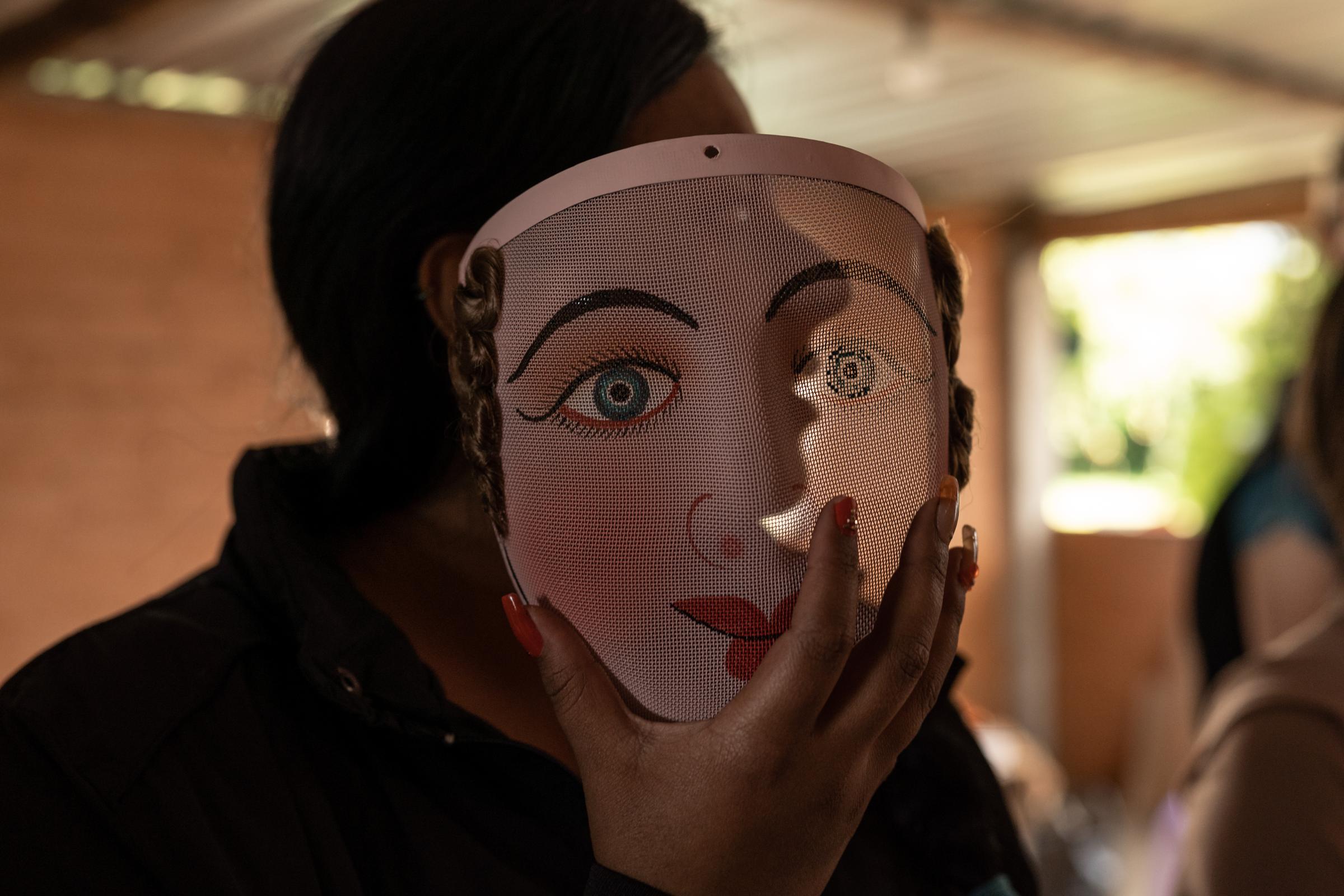 Los Diablos de Píllaro - A woman holds a wire frame, mesh mask of a Bailarina de...