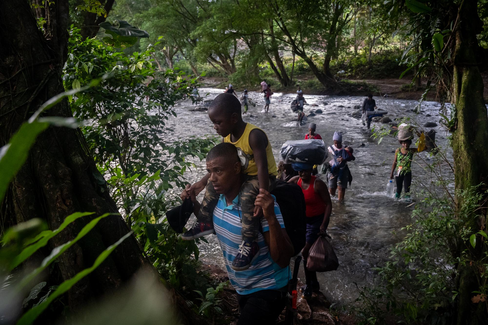 Inside The Derian Gap - A Haitian migrant carries his son through the Darien Gap...