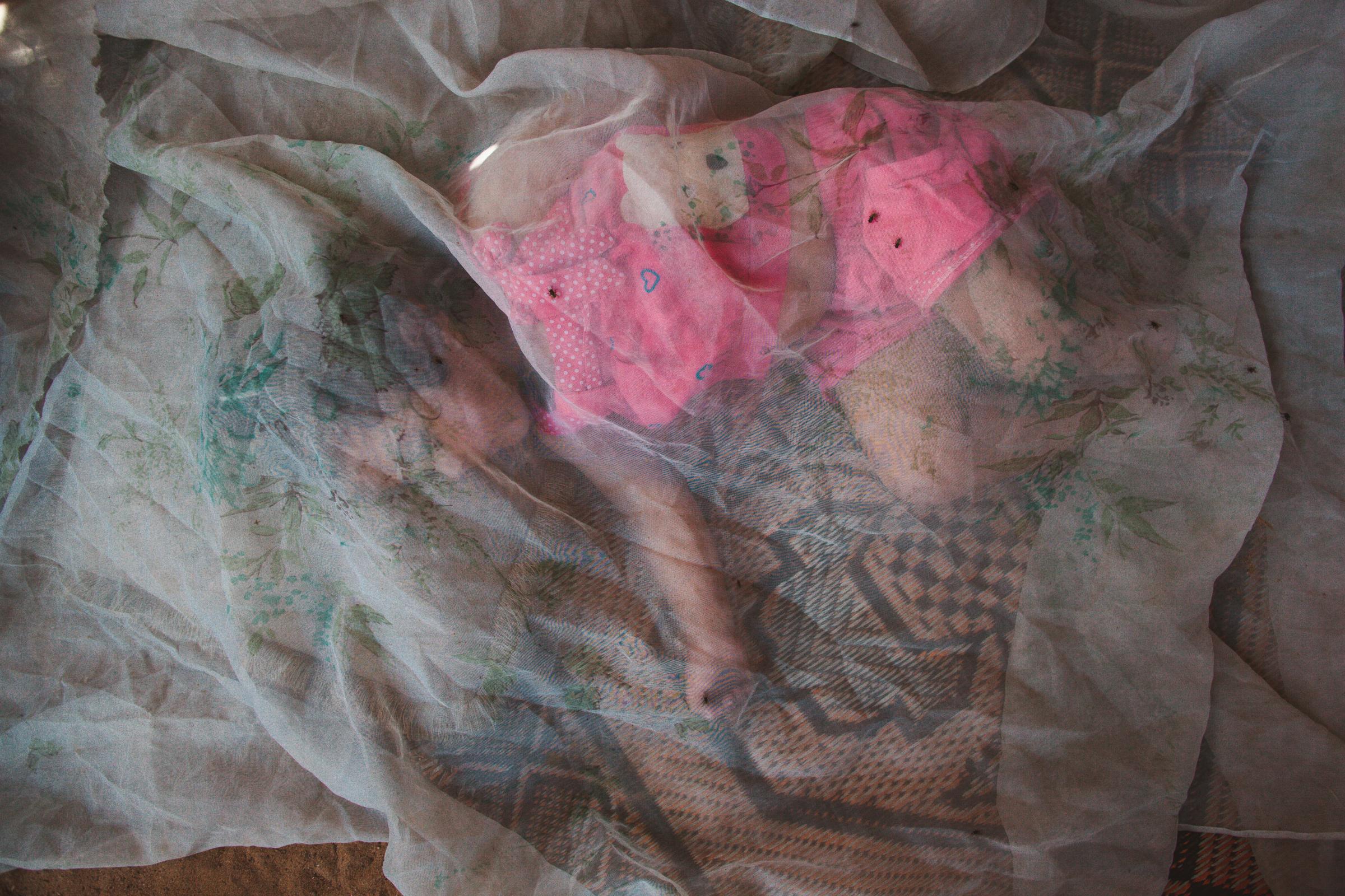 SINGLES - Salma Haimedan, 2, sleeps under a mosquito net outside...