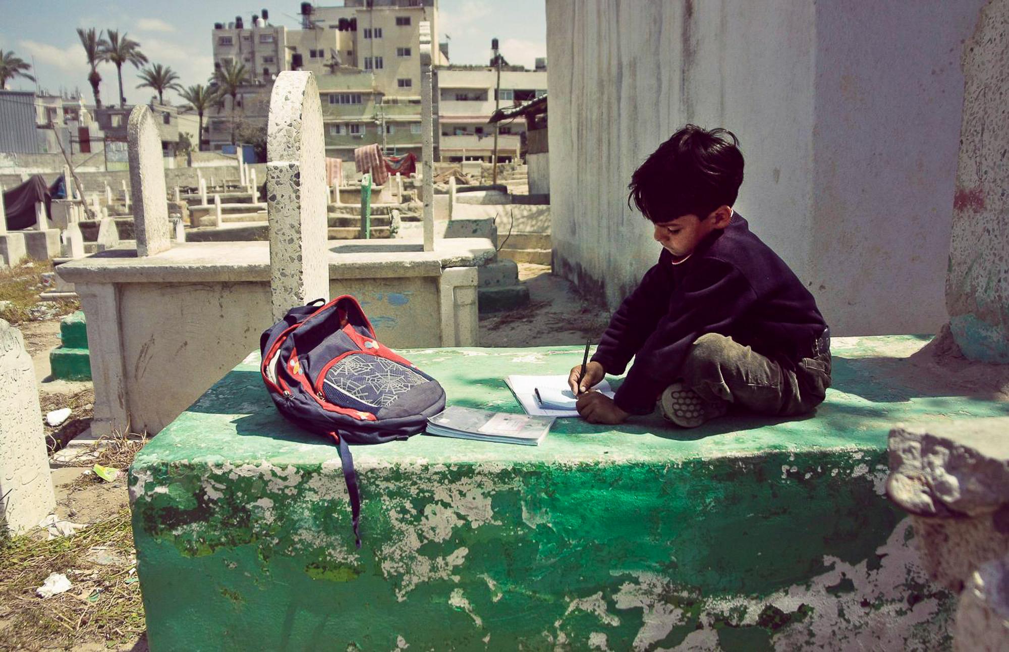 Life Under Siege - a Palestinian young boy writing his homework while...