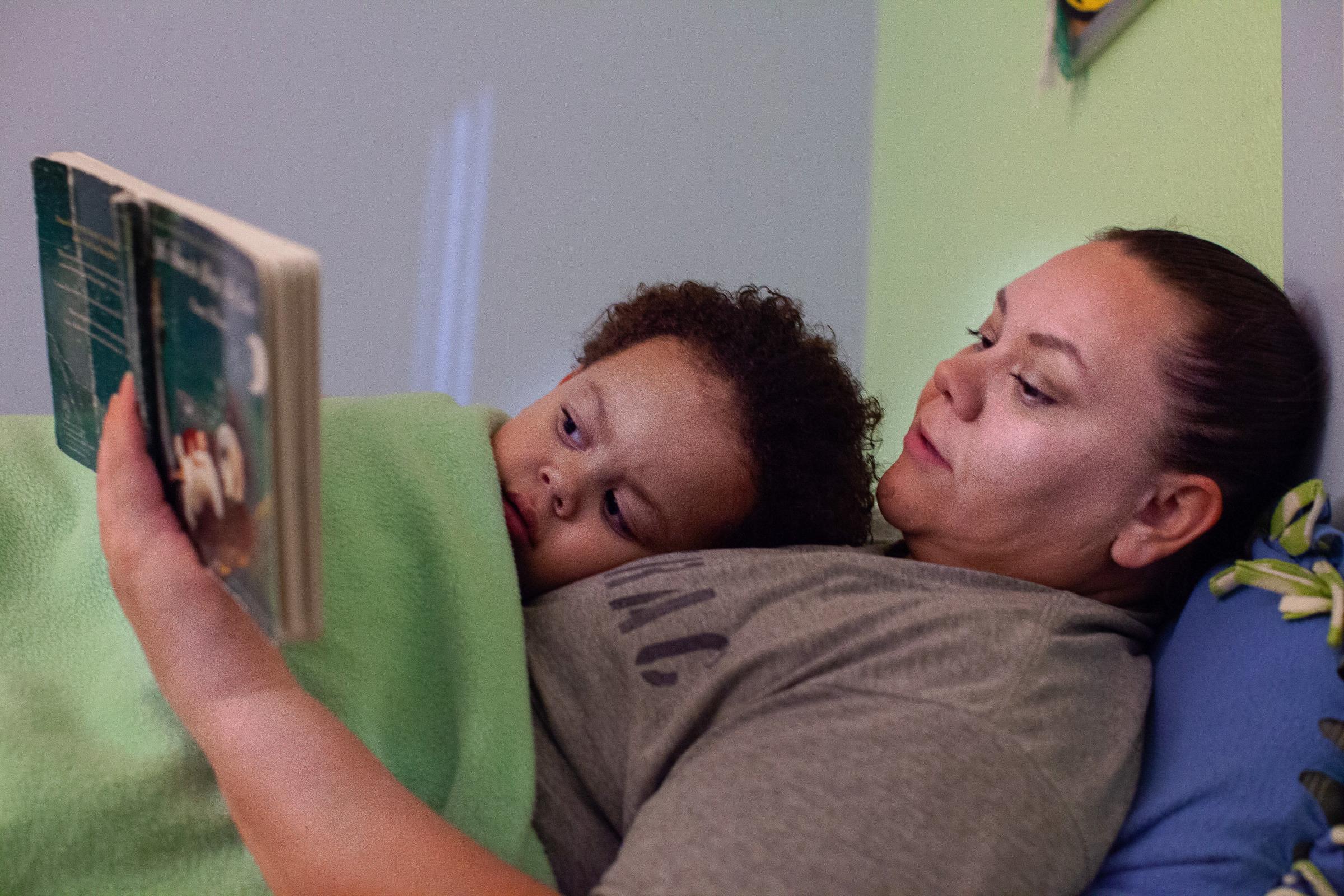 Crystal Lansdale laying in bed with her son Krishan while reading him a bedtime story inside her...