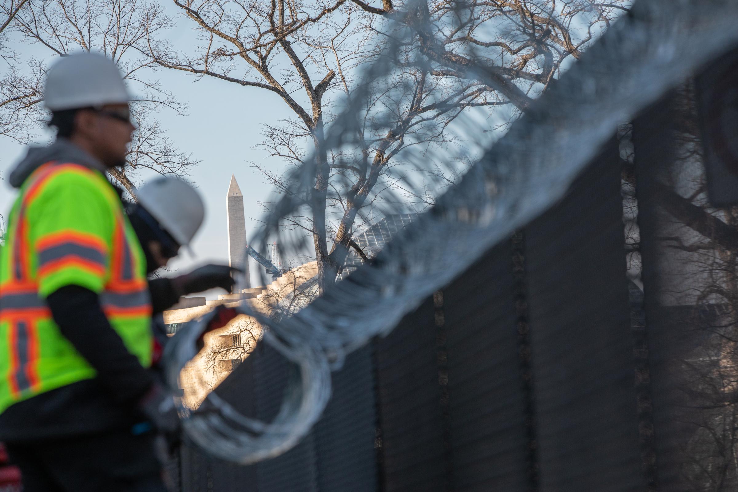 The Washington Monument is visible as workers install razor wire on top of fencing on Capitol...
