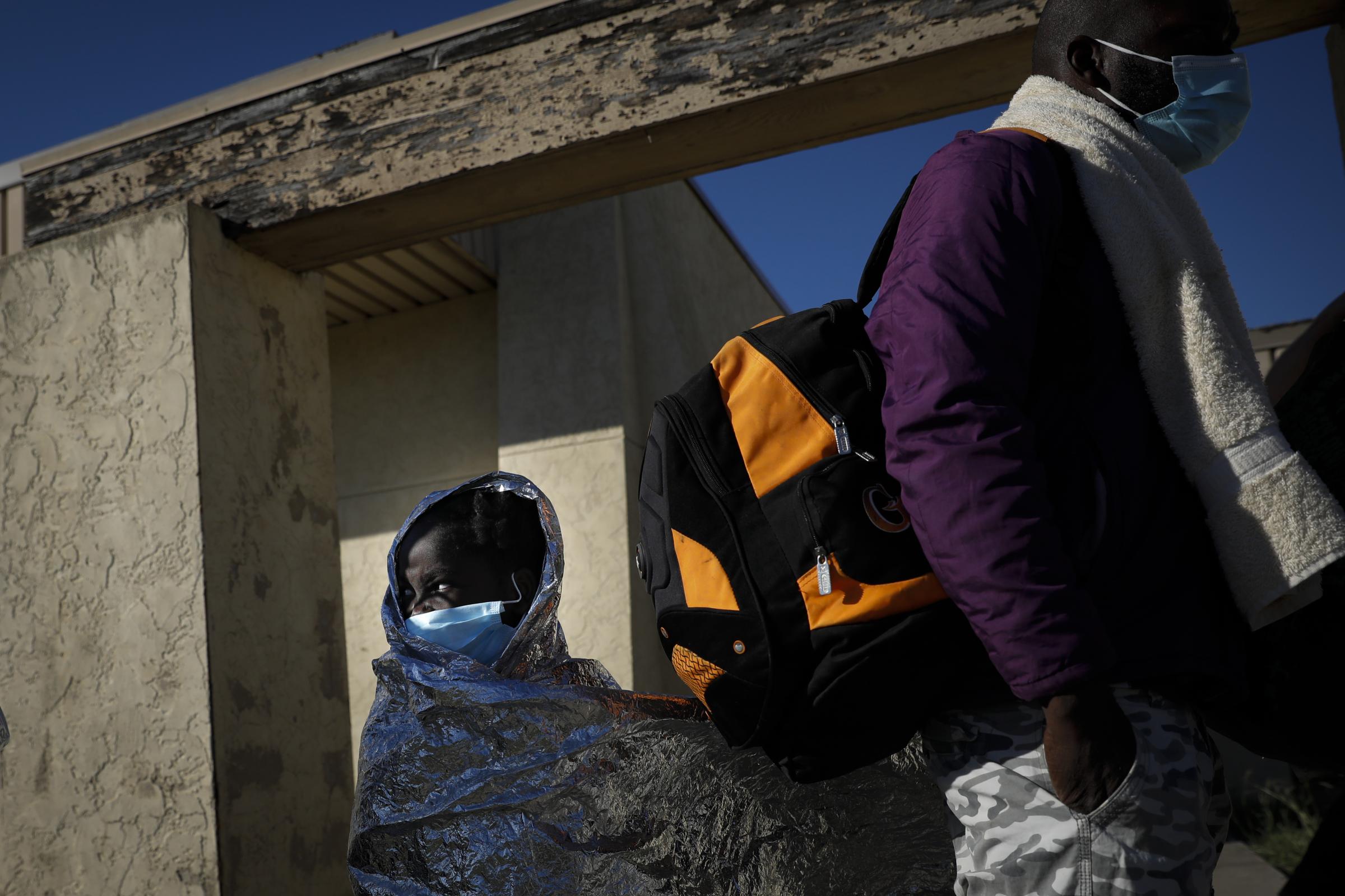 slideshow - A girl wrapped in an emergency thermal blanket waits in line with others migrants seeking asylum...