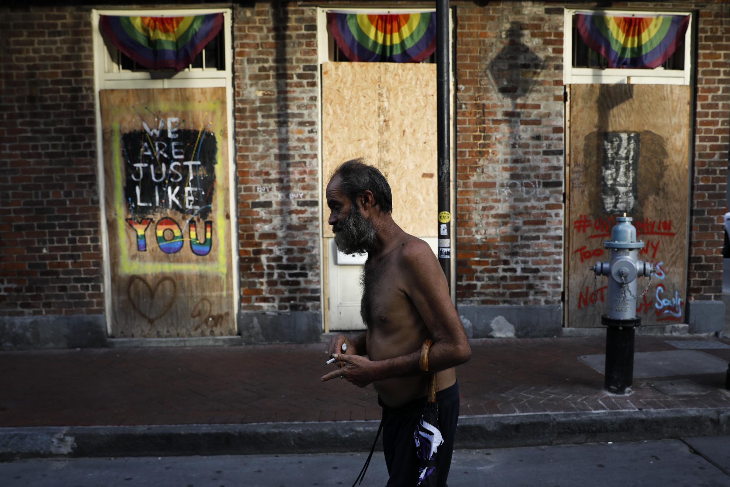 slideshow - A man walks past boarded up windows in Bourbon Street at the French Quarter after Hurricane Ida...