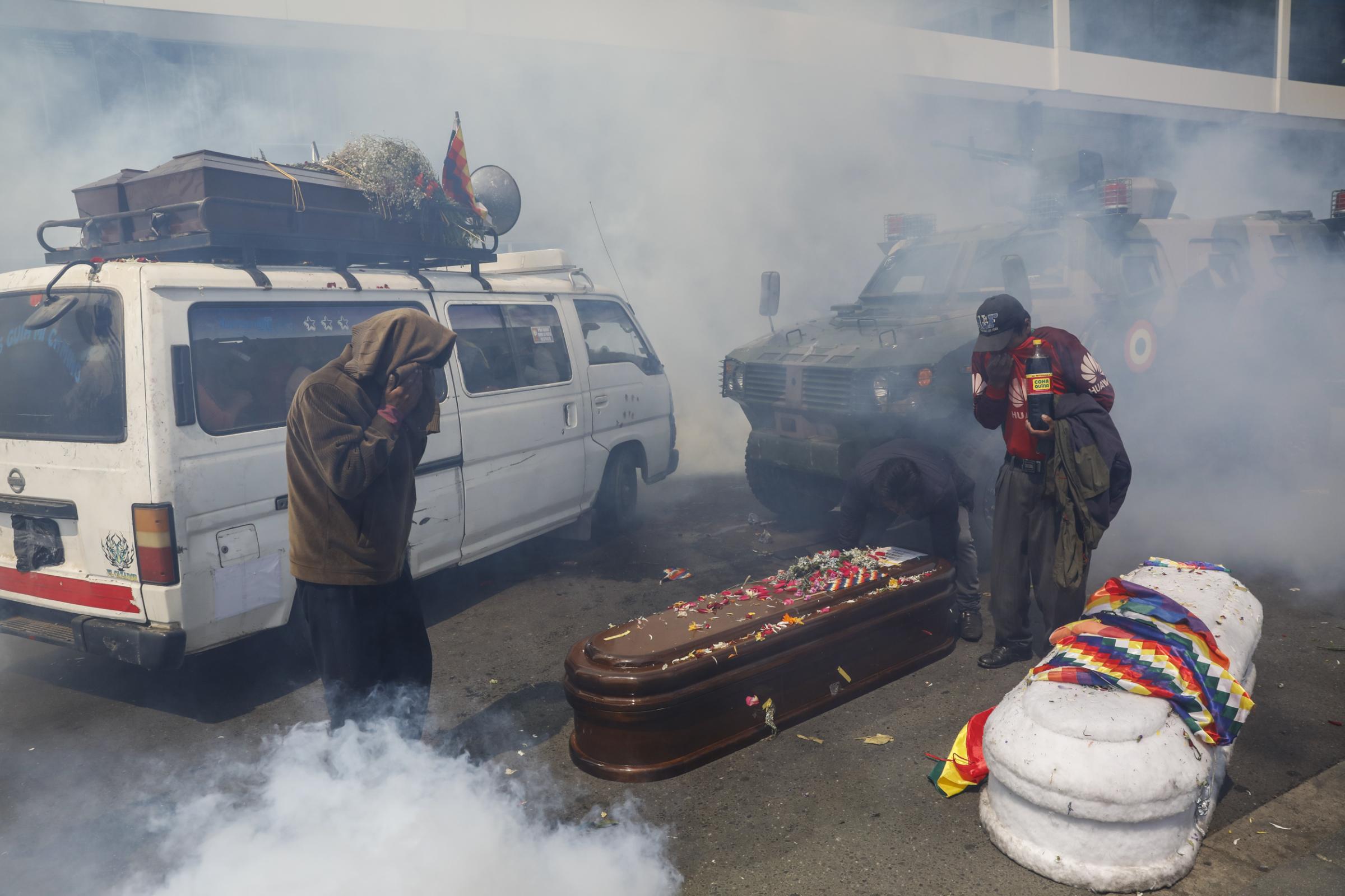 slideshow - Supporters of former Bolivian President Evo Morales take cover from tear gas while carrying...