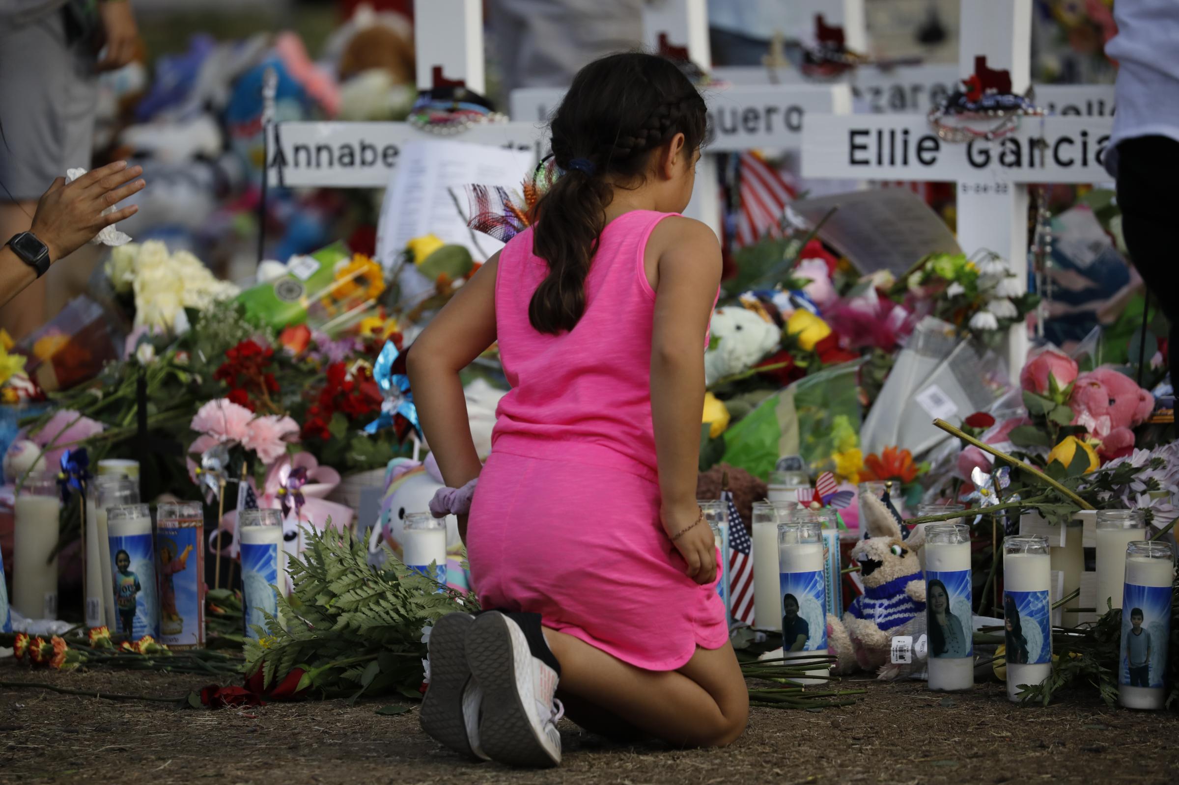 slideshow - A girl mourns in the memorial at Robb Elementary school, where a gunman killed 19 children and...