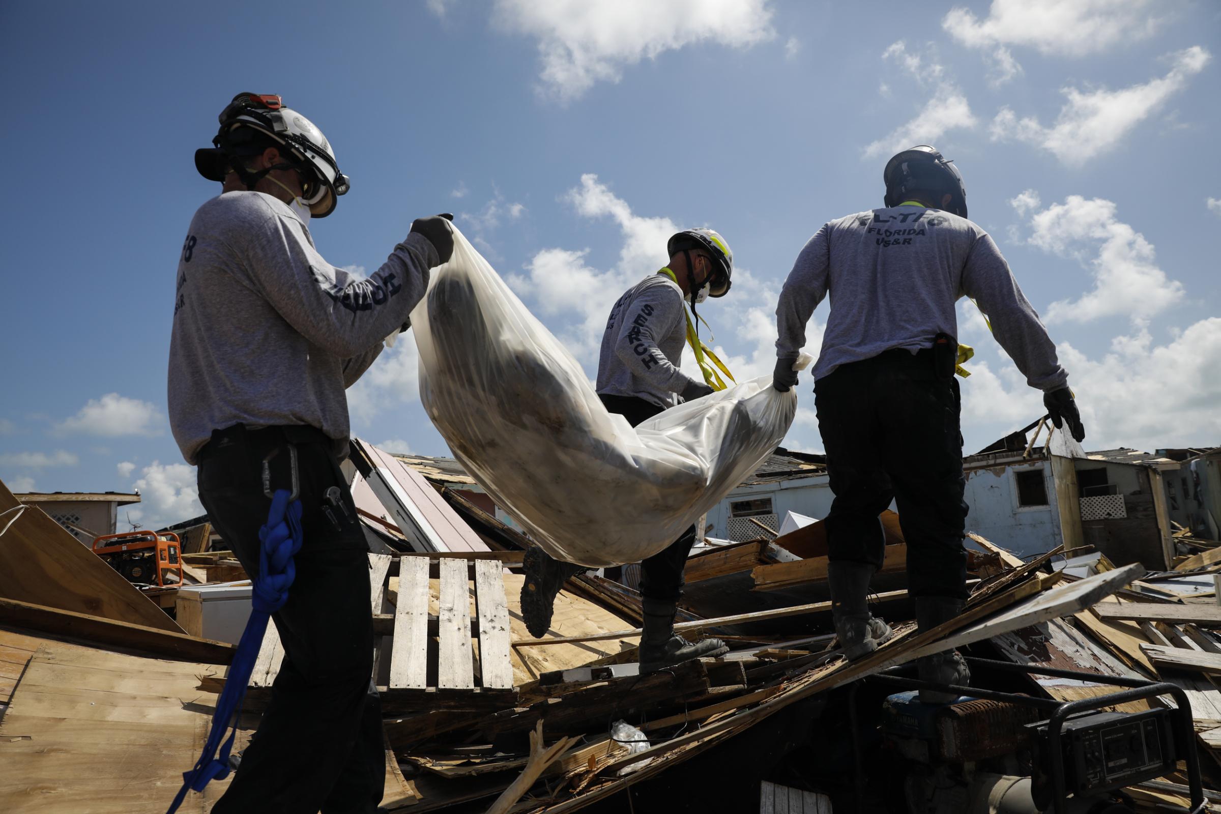 slideshow - Personnel from the Florida Seach & Rescue Task Force remove a body recovered in the destroyed...