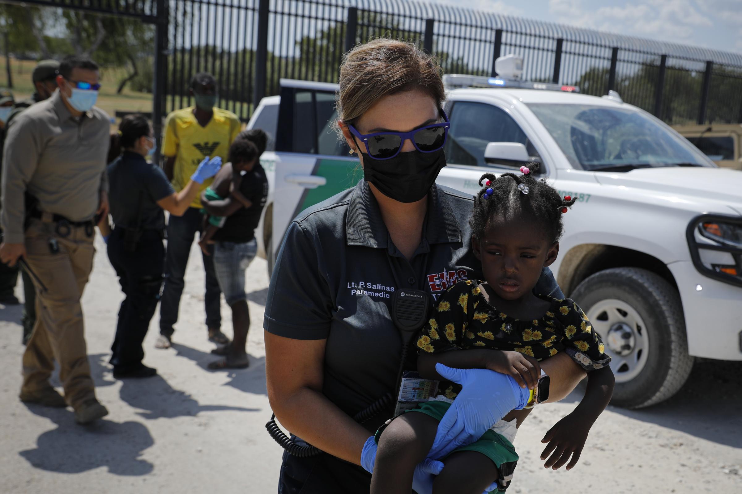 slideshow - A health worker carries a migrant seeking asylum in the U.S. near the International Bridge...