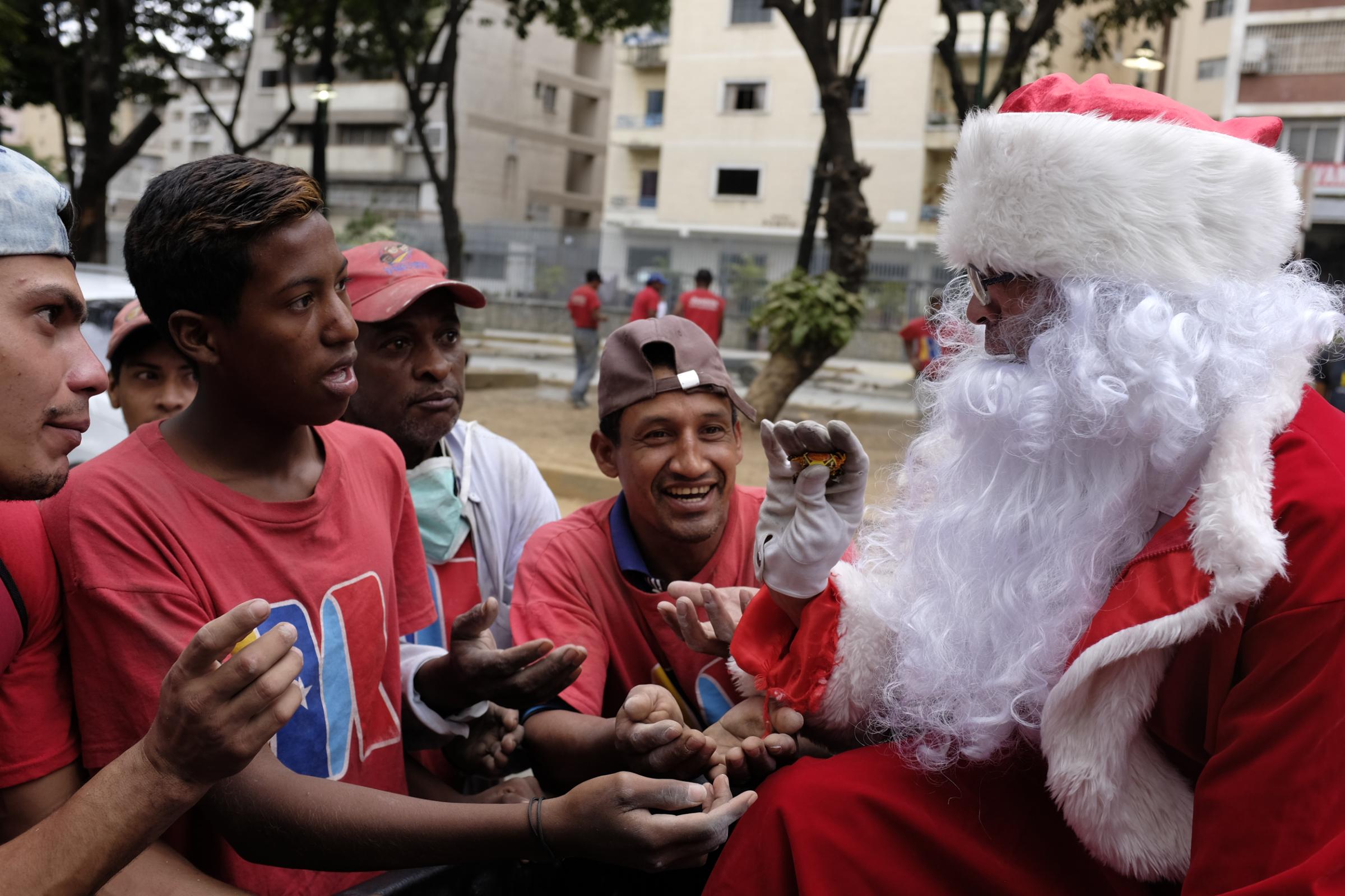 slideshow - Richard Gamboa, dressed up as Santa Claus, handouts candies to workers during the event...