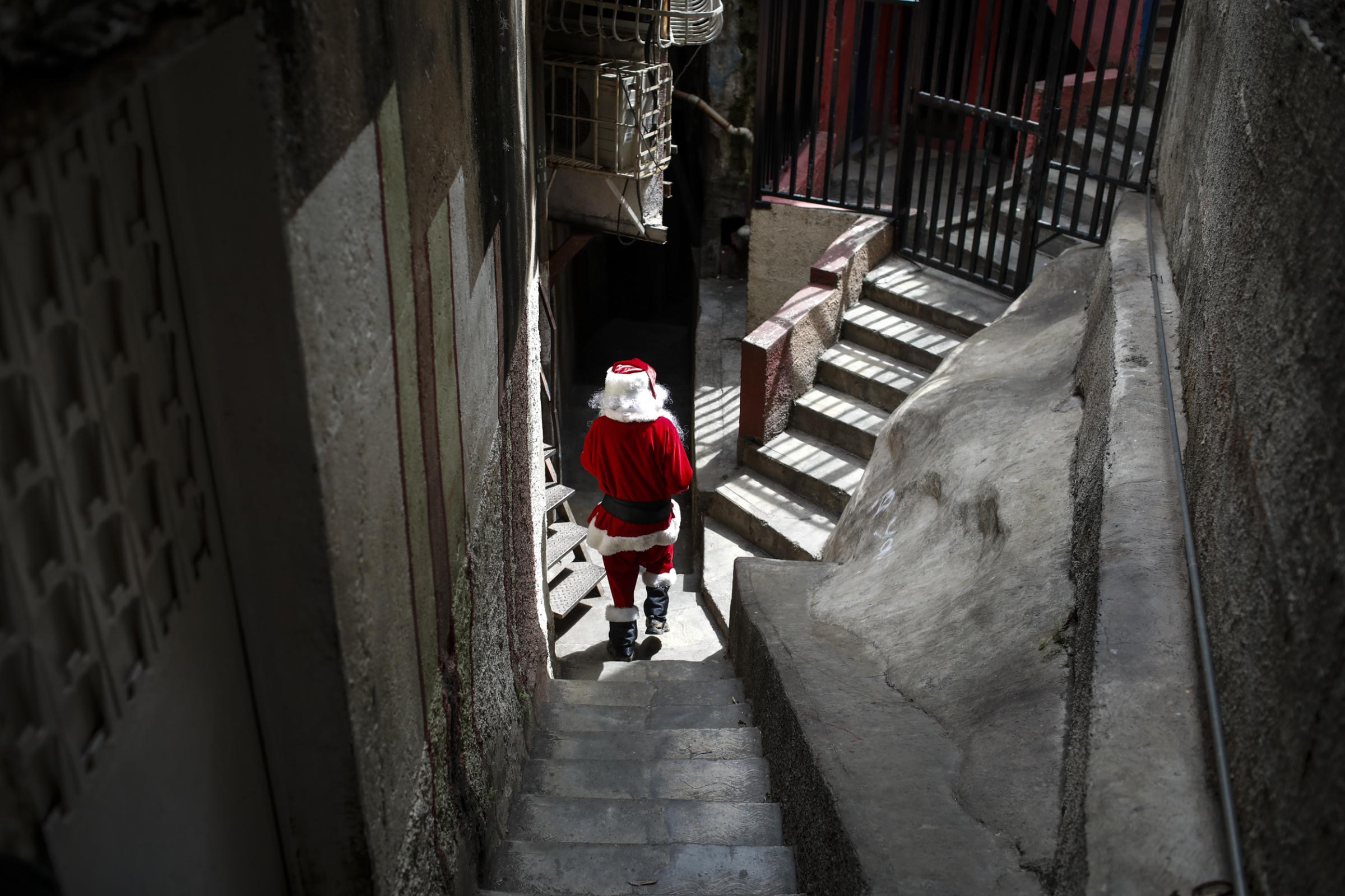 slideshow - Richard Gamboa, dressed up as Santa Claus, walks in a alley of the slum Cota 905 during the event...