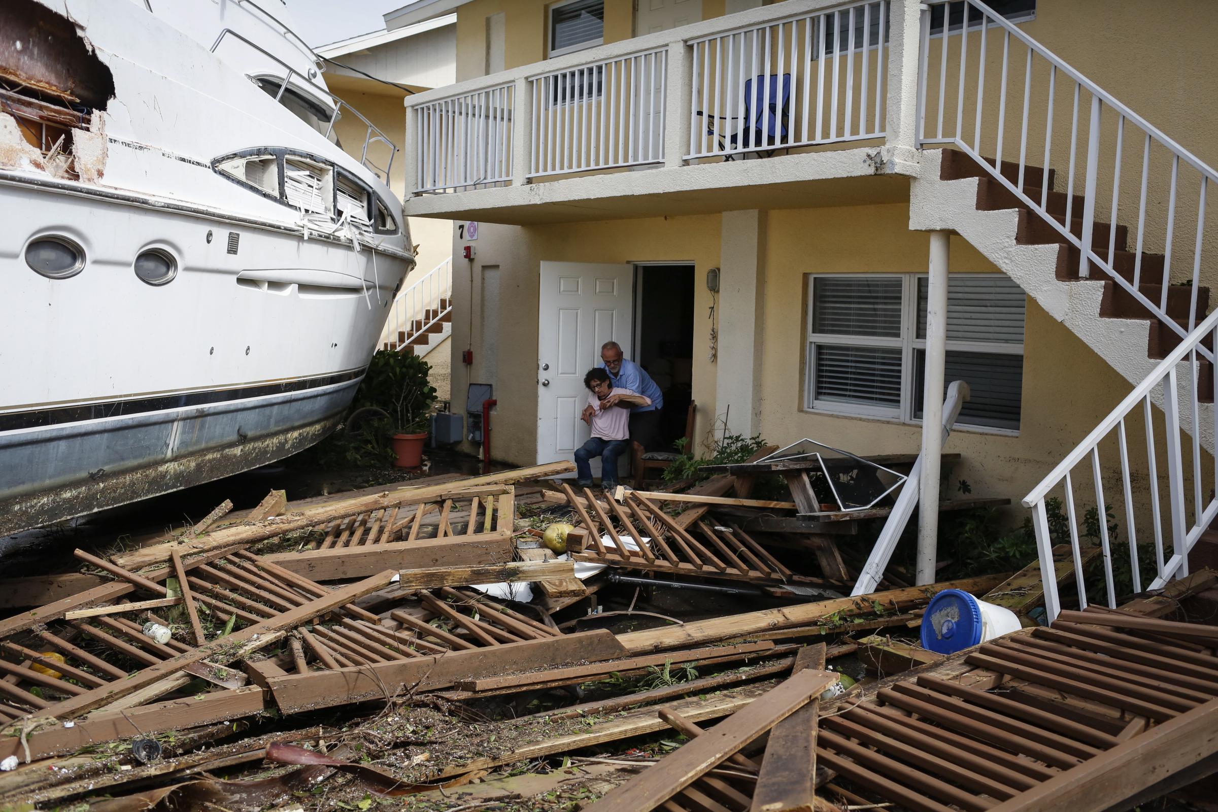 slideshow - A man helps a woman next to a damaged boat amid a downtown condominium after Hurricane Ian caused...