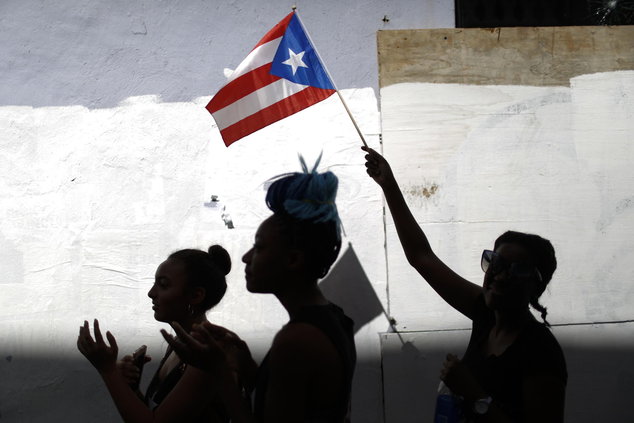 slideshow - A woman waves a Puerto Rican flag during ongoing protests calling for the resignation of Governor...