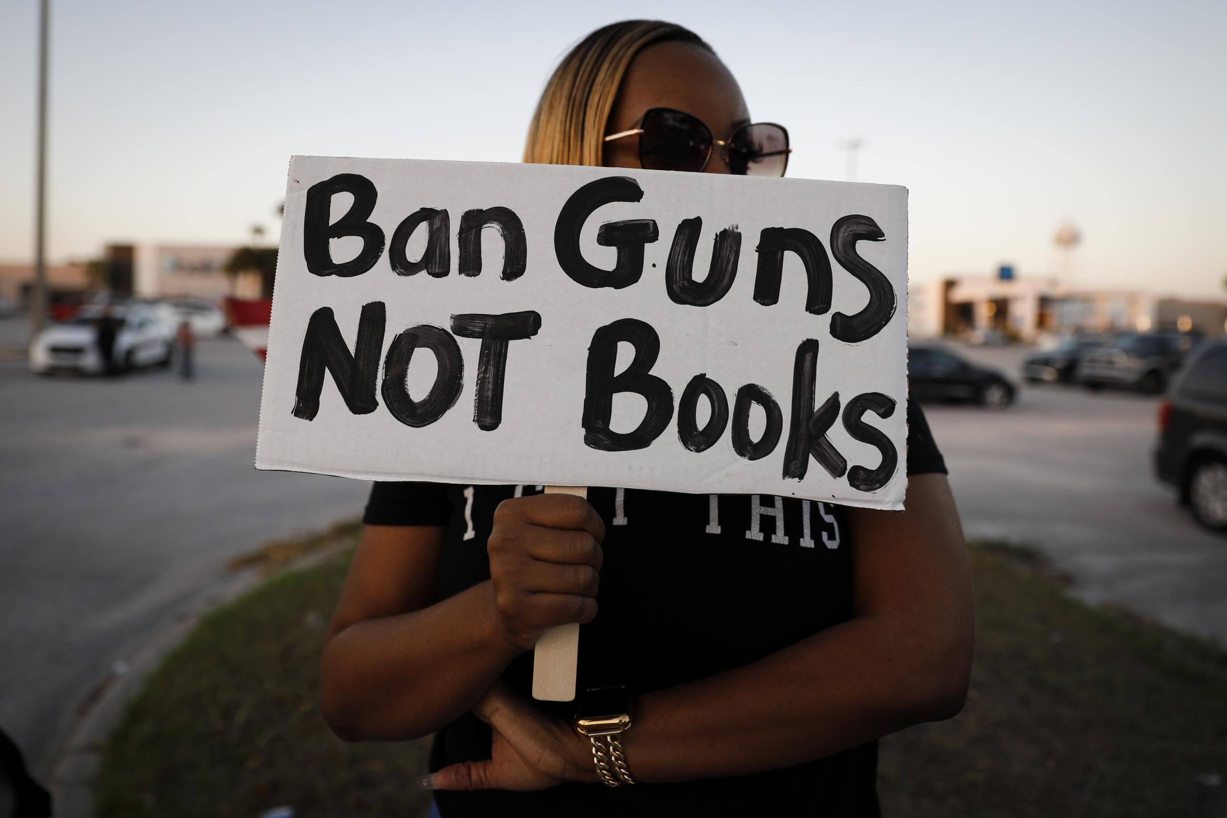 slideshow - A woman holds a sign during a gatering outside a Books-a-Million bookstore where Florida Governor...