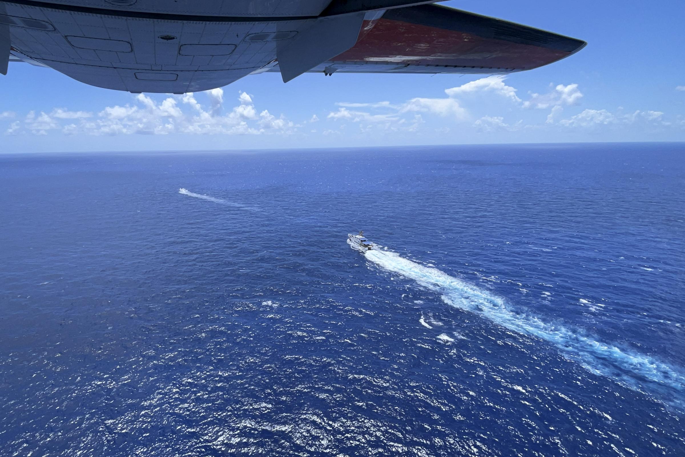 slideshow - U.S. Coast Guard vessels are seen from the open hatch of an HC-144 Ocean Sentry aircraft during a...