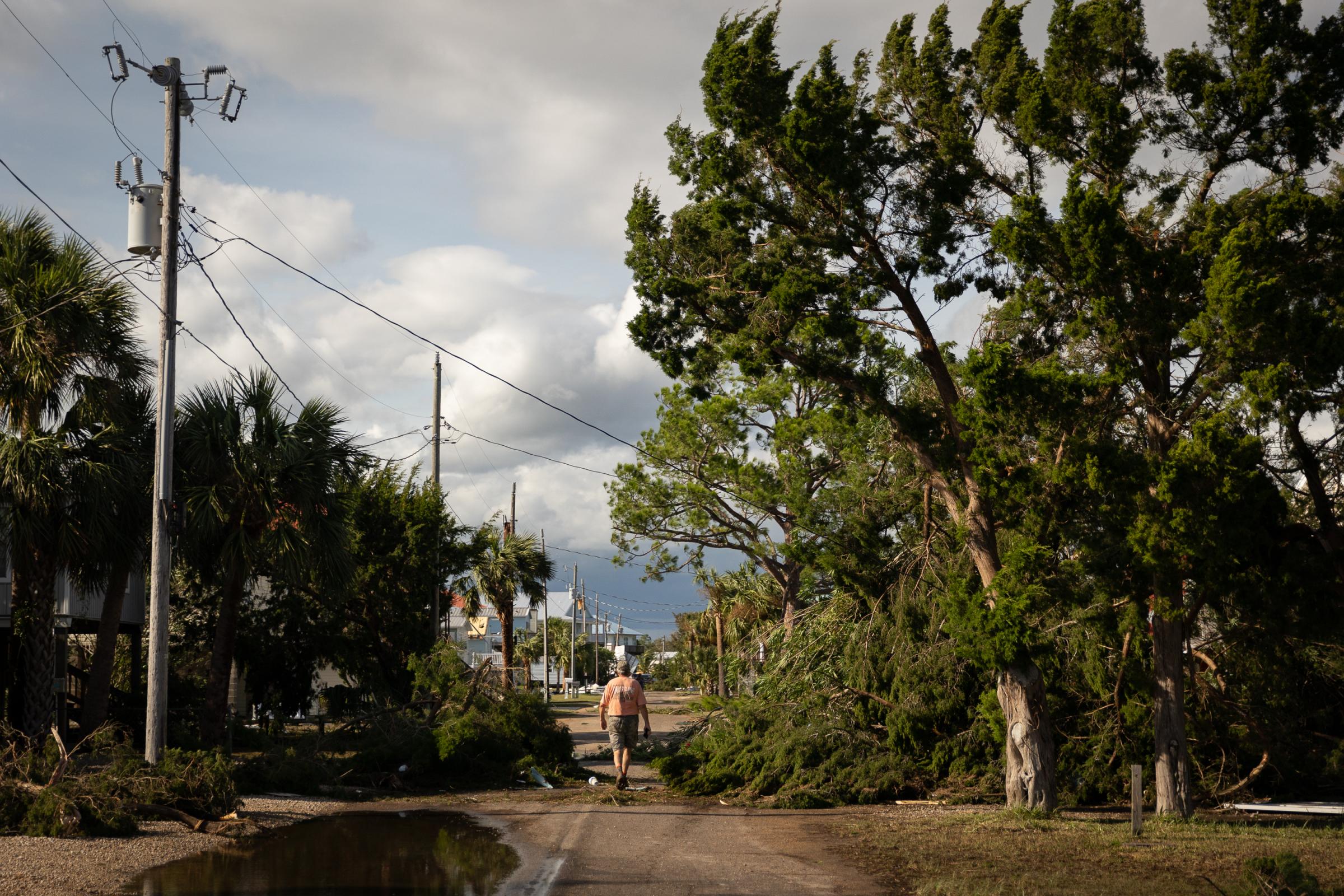 Hurricane Idalia hits Florida - A person walks near fallen tree branches in Keaton Beach,...