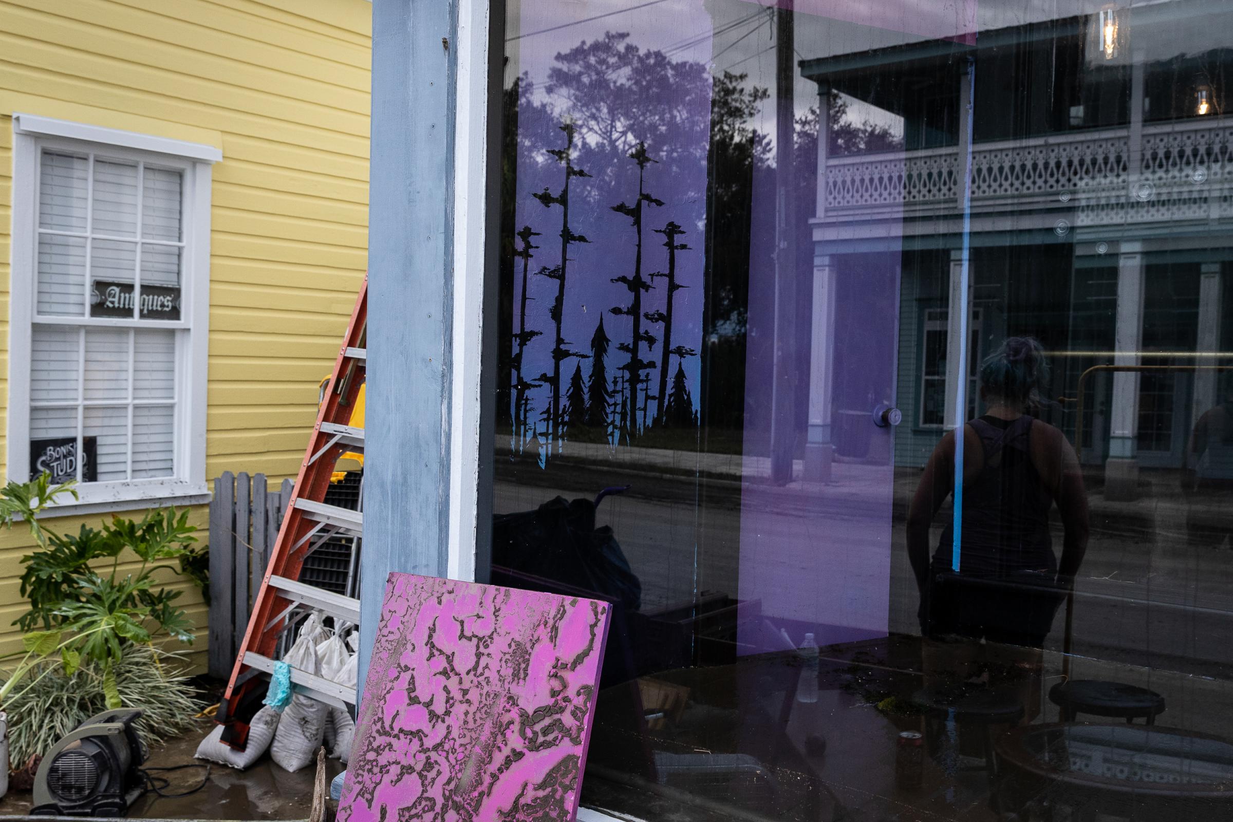 Hurricane Idalia hits Florida - A woman is seen reflected in a window as she cleans up a...