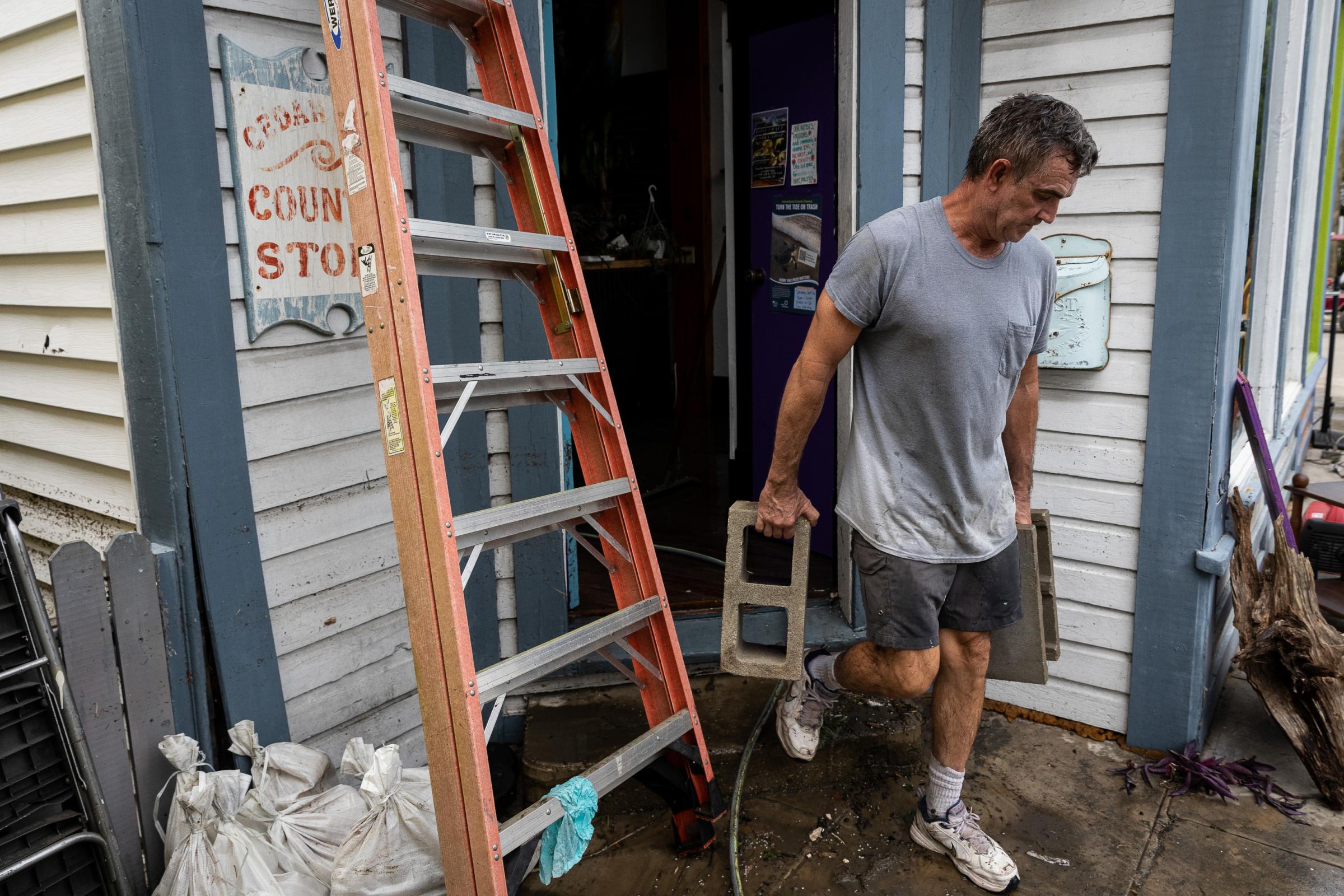Hurricane Idalia hits Florida - A man carries bricks as he clean up a coffee shop after...