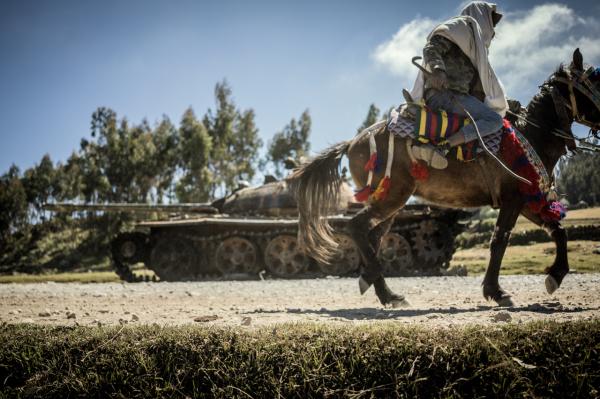 Amanuel Sileshi | Searching for Peace Amidst Chaos -  A horse and rider pass a destroyed tank in Mesobit on...
