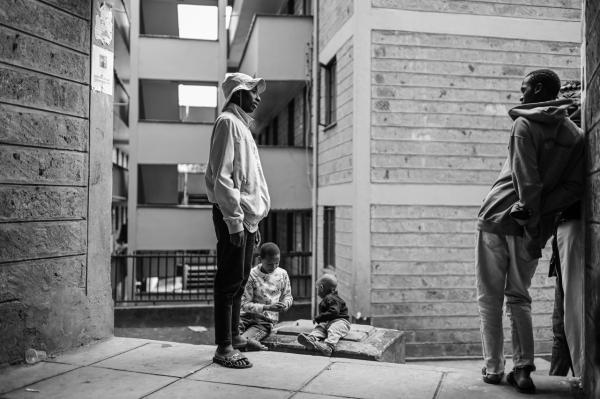 Image from Gordwin Odhiambo | A Changing Community and the Fears Ahead -  Yugo Dennis talks with his friends outside the apartment...