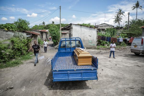 Image from Ericky Boniphace | Even The Dead can't Escape Climate Change -  People walk past a truck bearing a coffin with human...