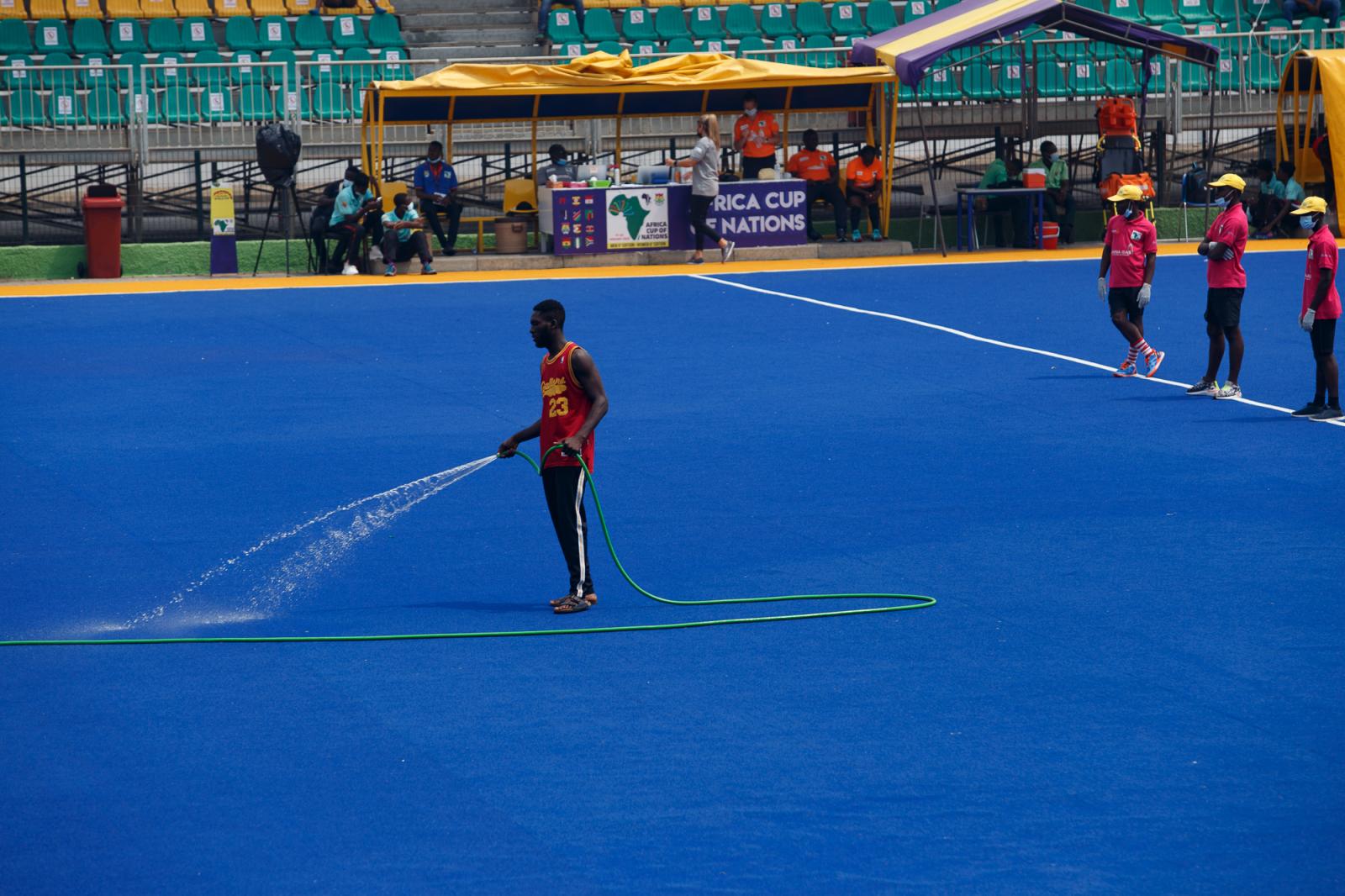 A worker sprinkles water on the...ey tournament, in Accra, Ghana.
