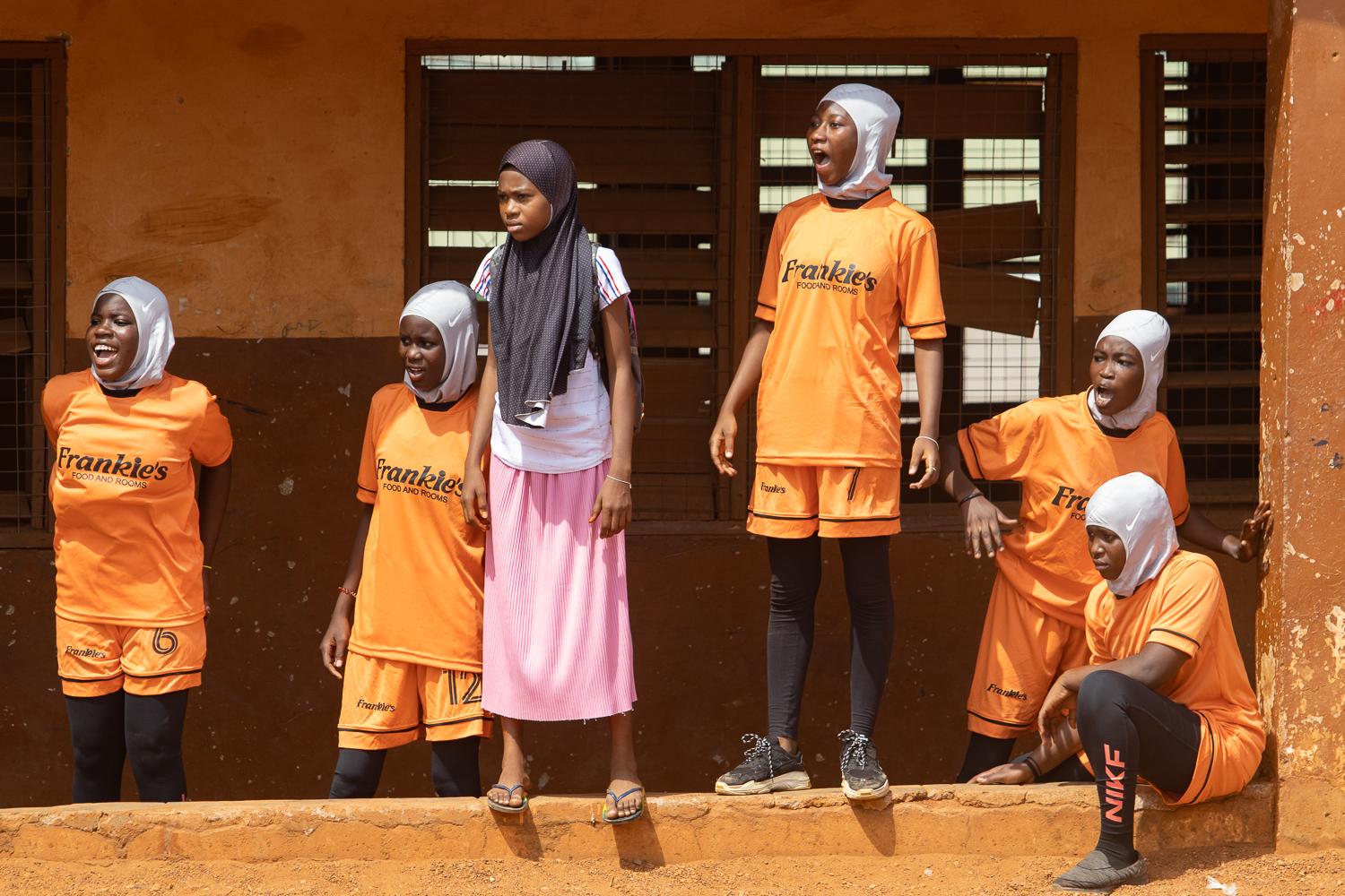 Image from Faith and Football - Some girls react to teammates playing football during the...
