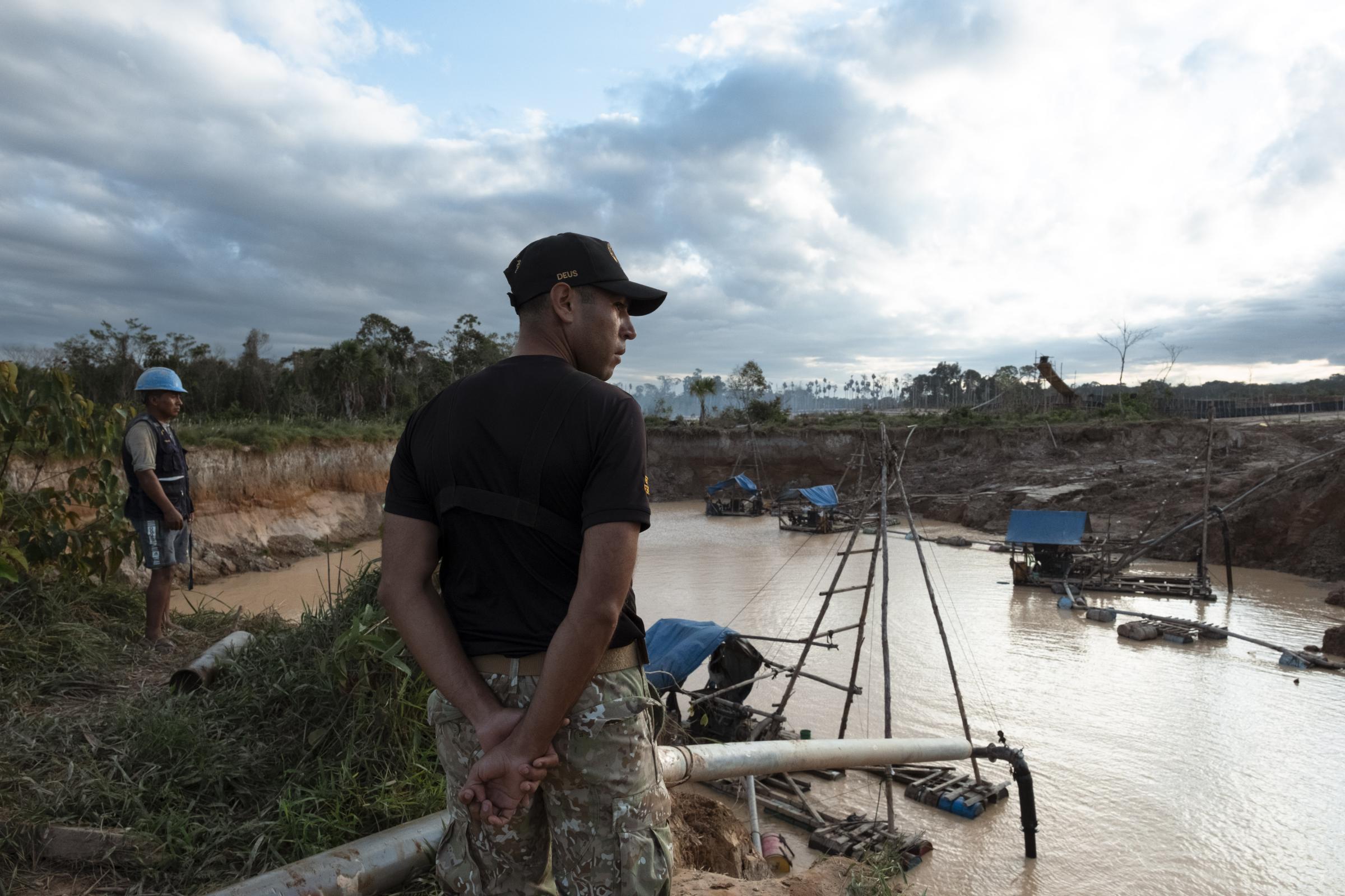 Paradise lost: Inside Peru's emergency zone for NBC News - A military man, next to a miner, observes the pit from which gold is extracted. The mining camp...