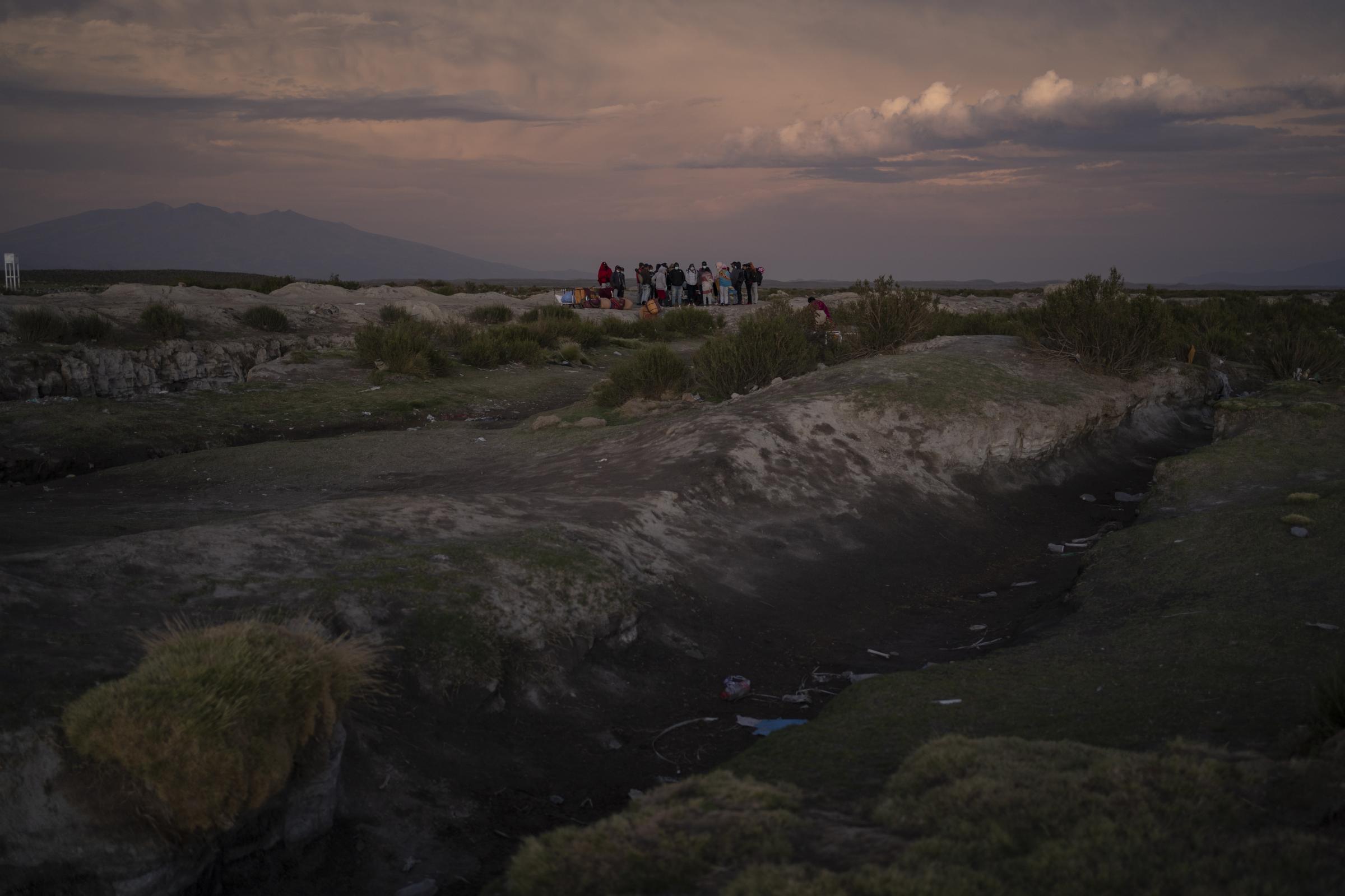 Colchane  -   Un grupo de migrantes espera para cruzar la frontera de...