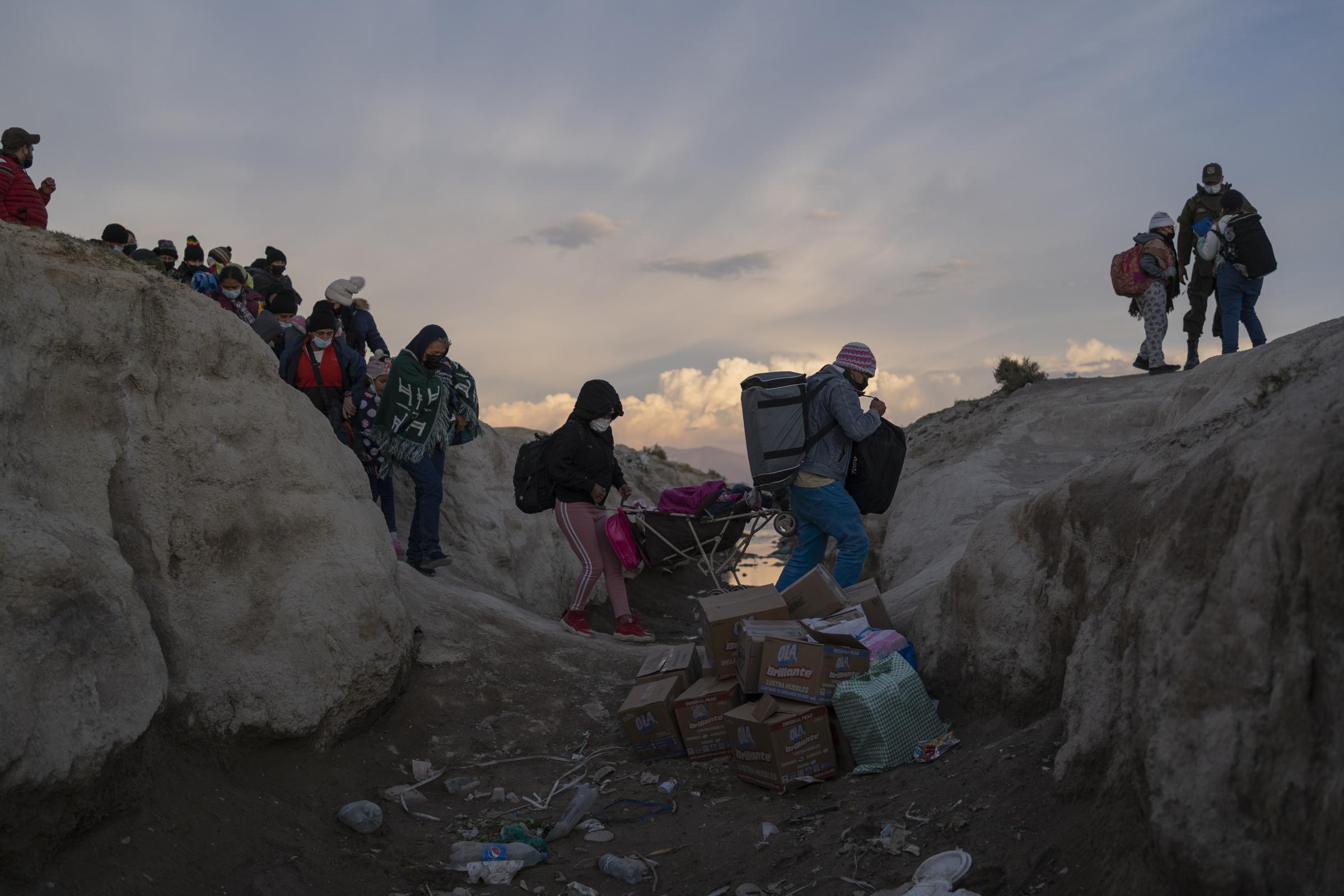 Colchane  -   Un grupo de migrantes cruza la zanja que separa Bolivia...