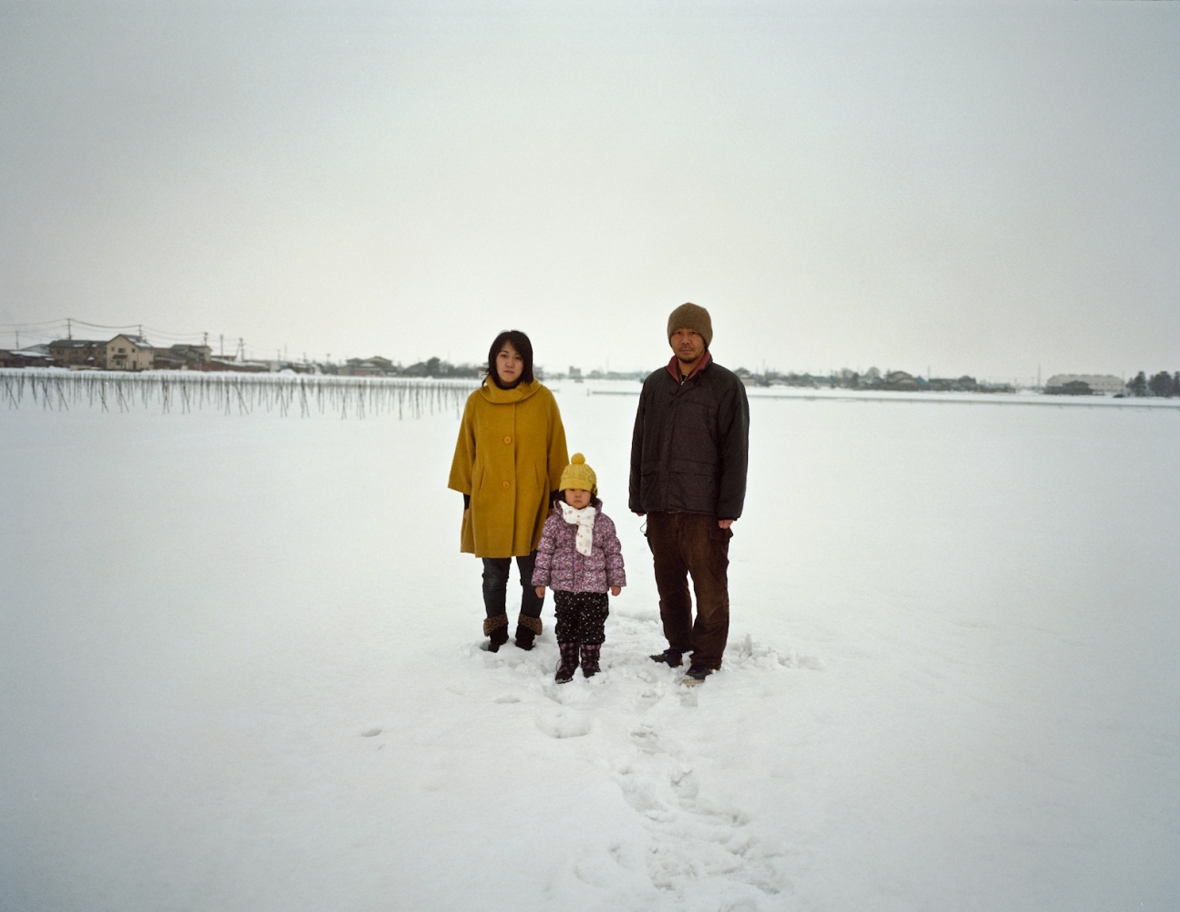  Nozaki and his family stand for a portrait in a snow covered vegetable field in the town of Aizuwakamatsu, Fukushima Prefecture. Nozaki and his wife are not overly concerned about radiation contaminating food and water, but how discrimination will impact the future for their 4 year-old daughter. Feb. 2014 