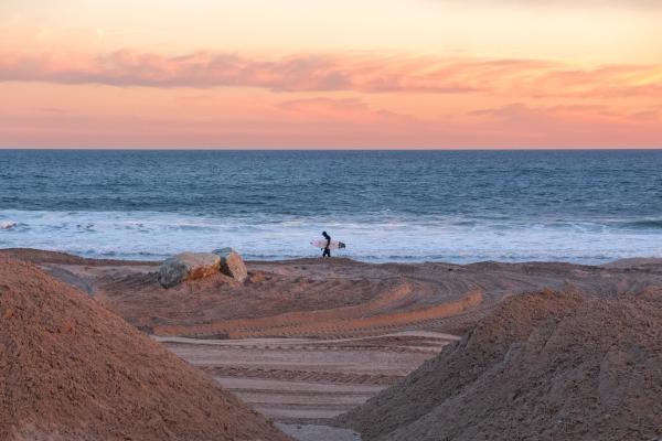 Image from Rockaway Beach - 13 Feb. 2023. Rockaway Beach, NY. Lone surfer walkiing...