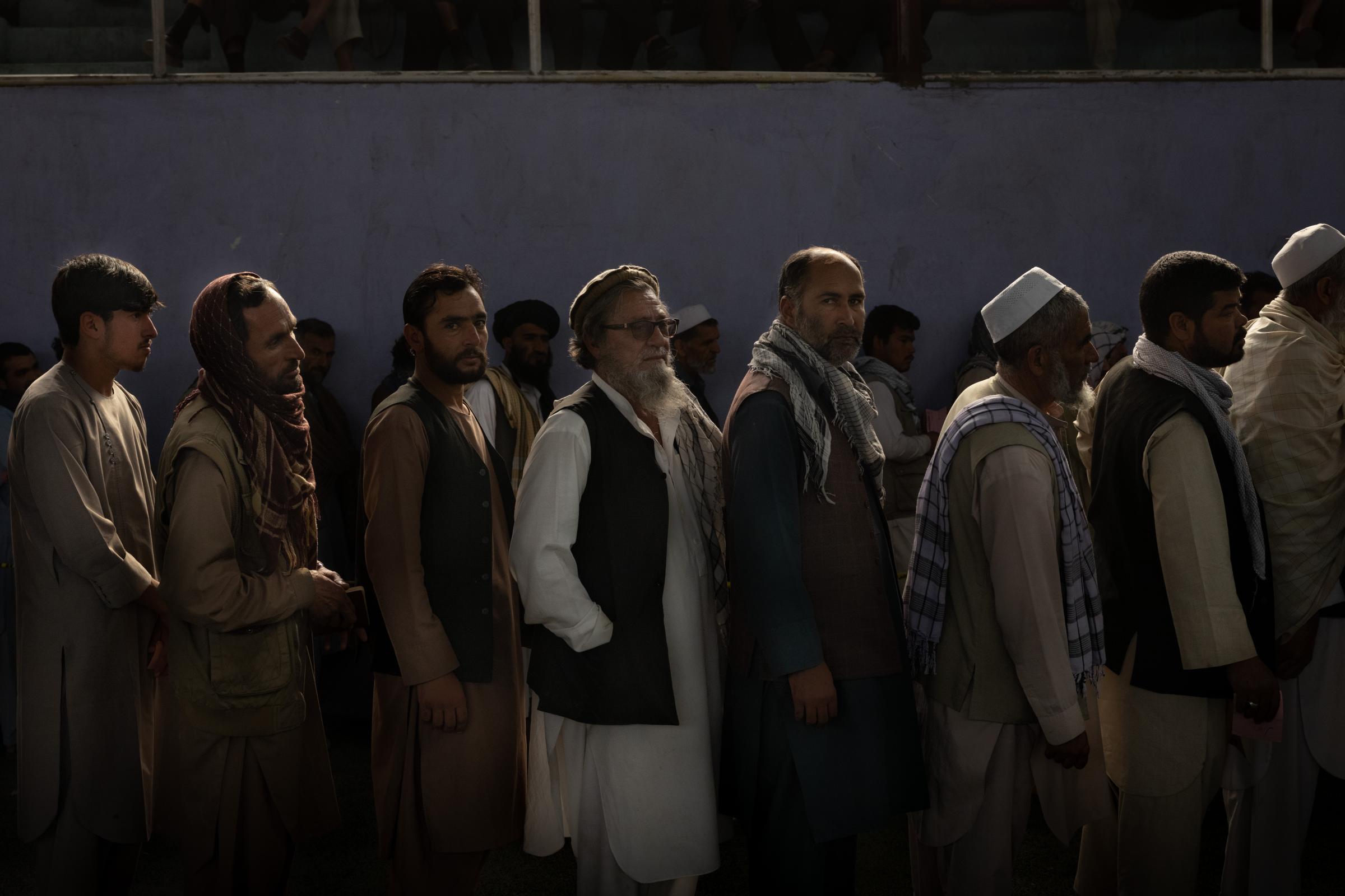 Men from Kabul&#39;s PD6 district wait for food packages of flour, beans and oil distributed...
