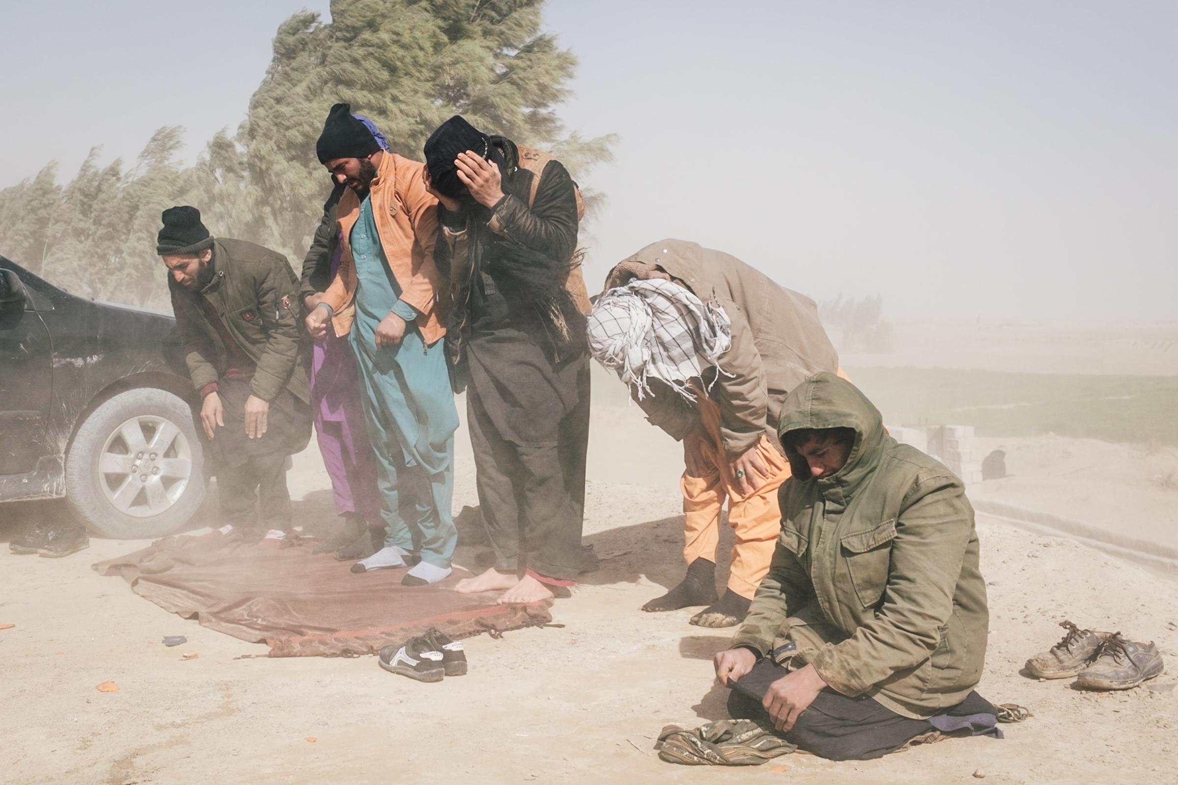 Afghanistan I Exodus - Travellers take a prayer break on the way through the...