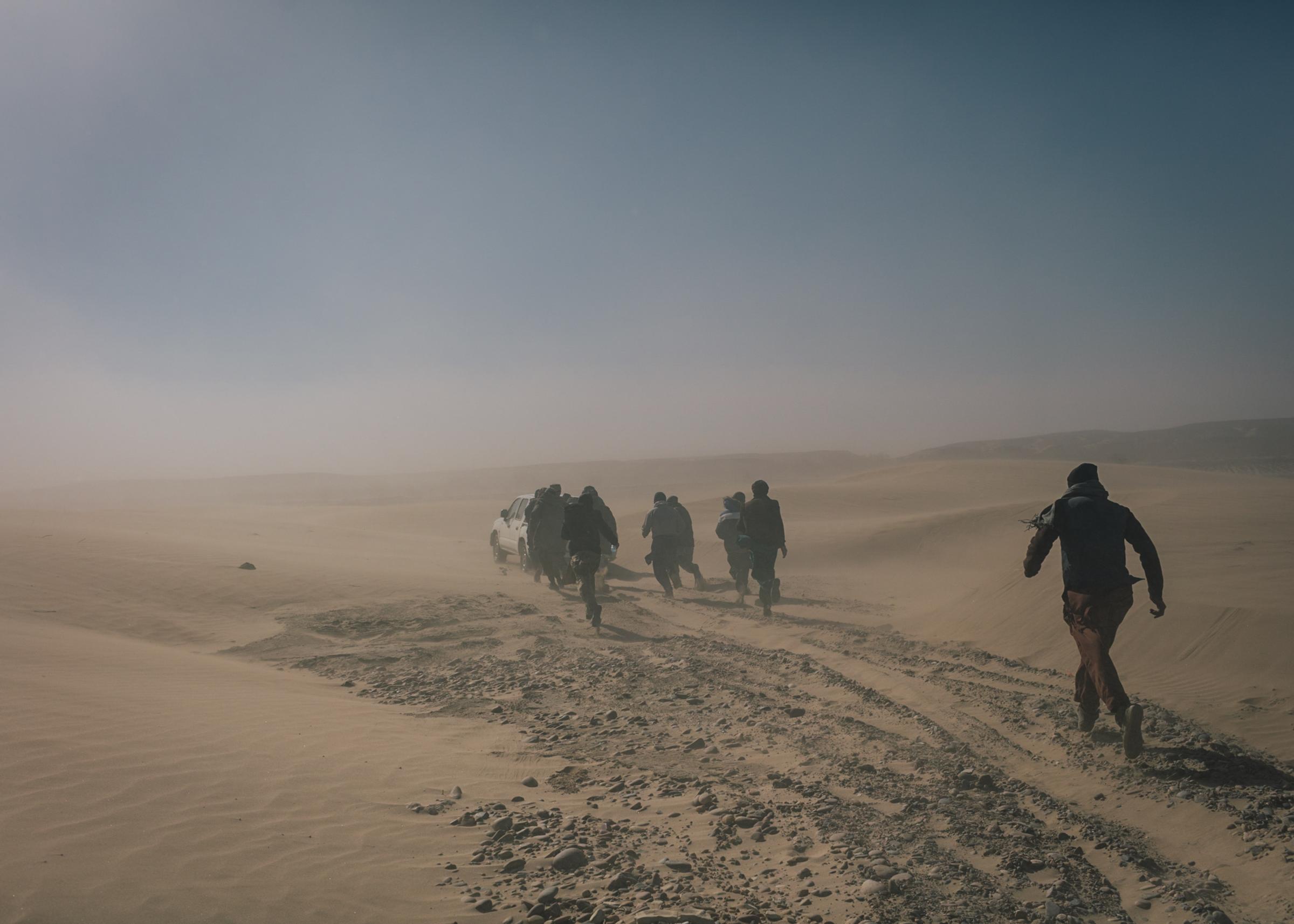 Refugees ran through a sand storm on the way through the desert.